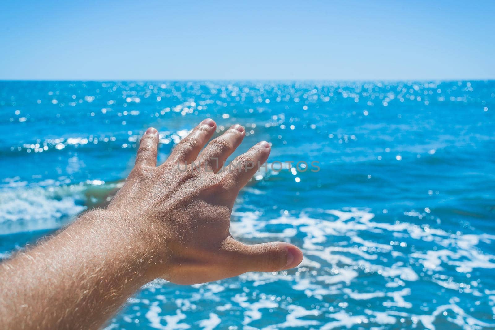 The young man stretched his hand forward to the sea and sky on the beach. The concept of freedom and rest at sea.