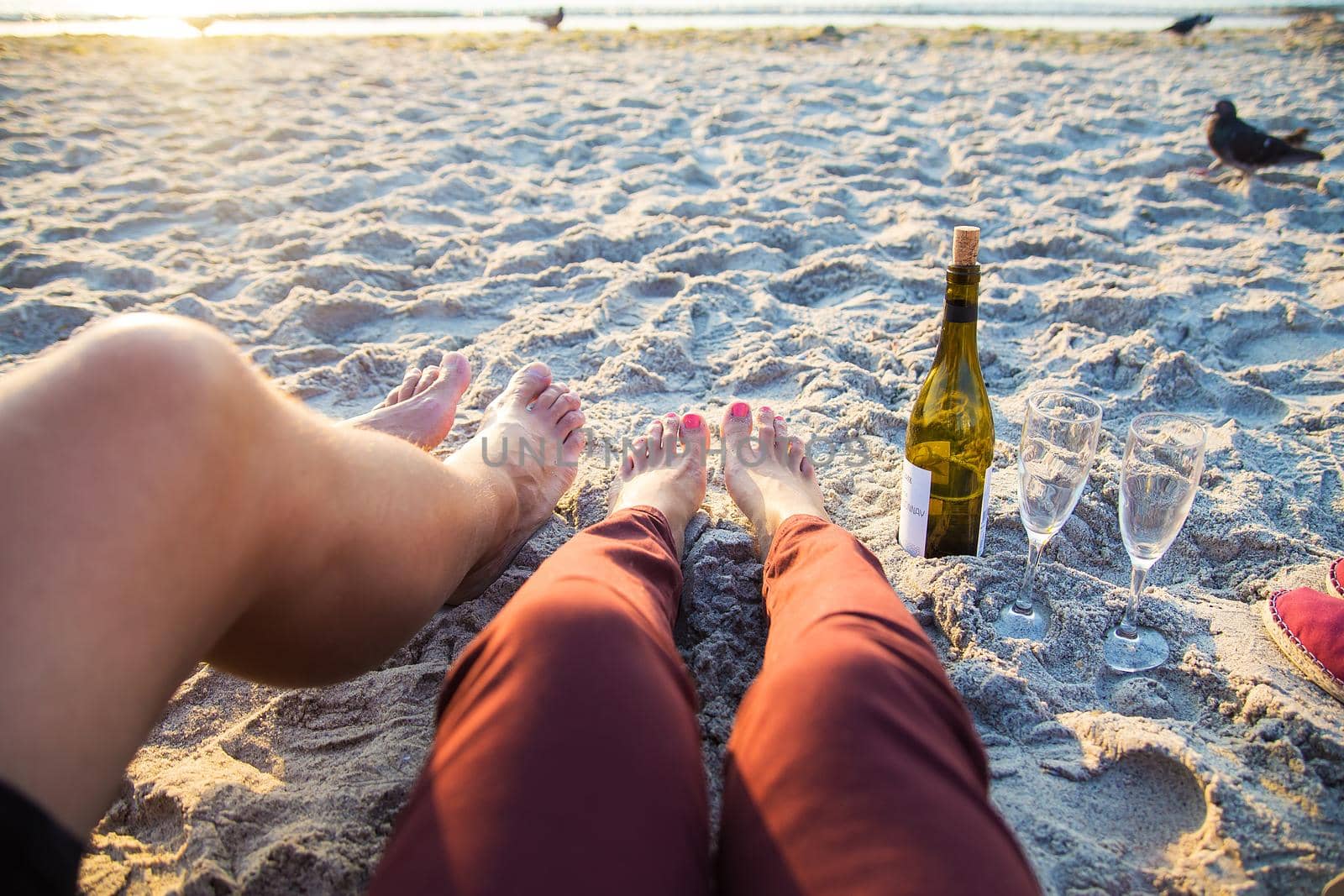 Happy stylish pair of legs on beach sunbathing, drinking wine by sfinks