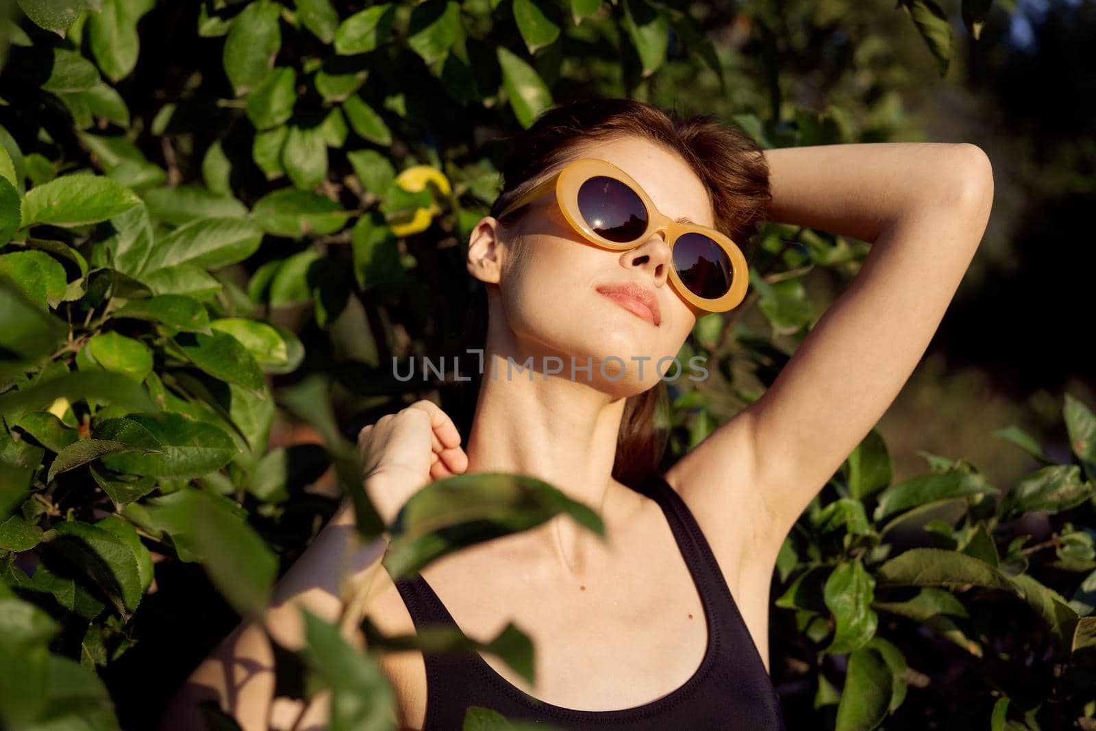 pretty woman in black swimsuit sunglasses green leaves nature. High quality photo