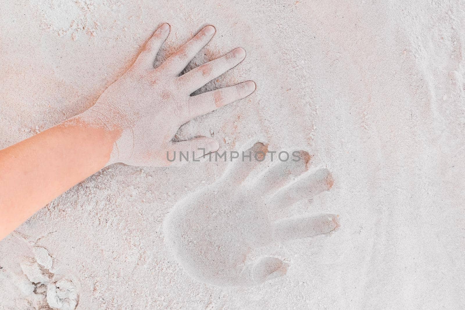 Trace or handprint of a young girl close up on the white beach sand background.