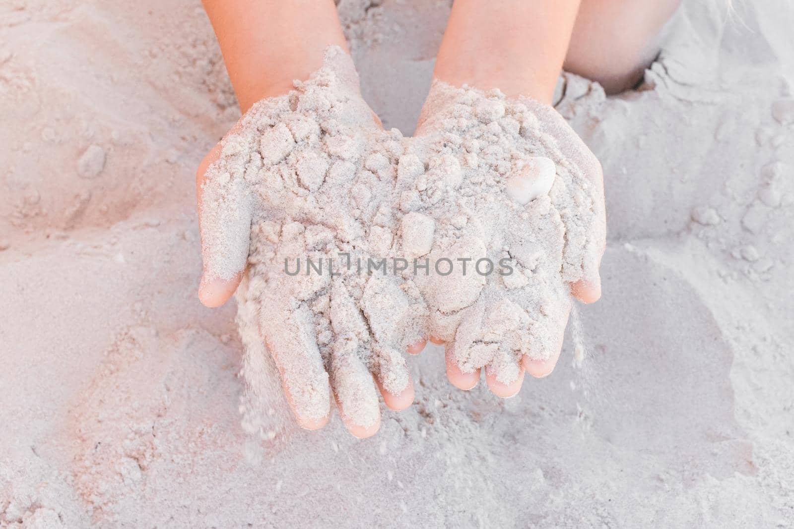 The hands of a young girl hold a pile of white sand close-up by AYDO8