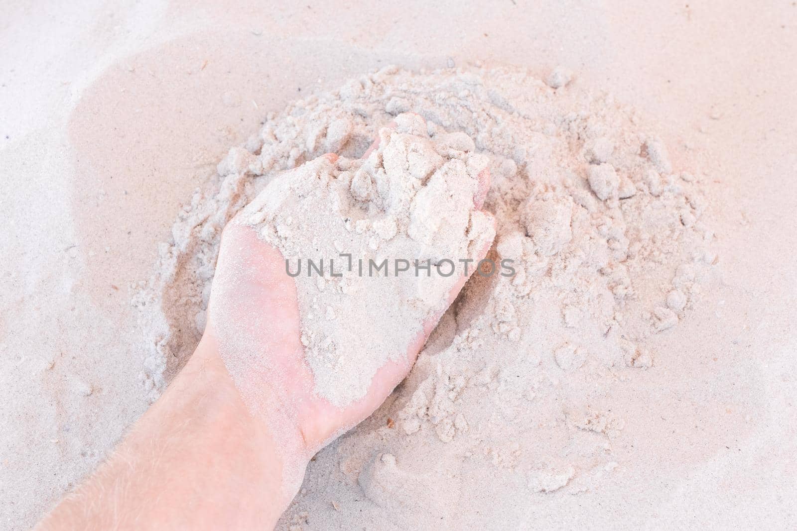The guy's hand takes or touches the white beach sand close up by AYDO8