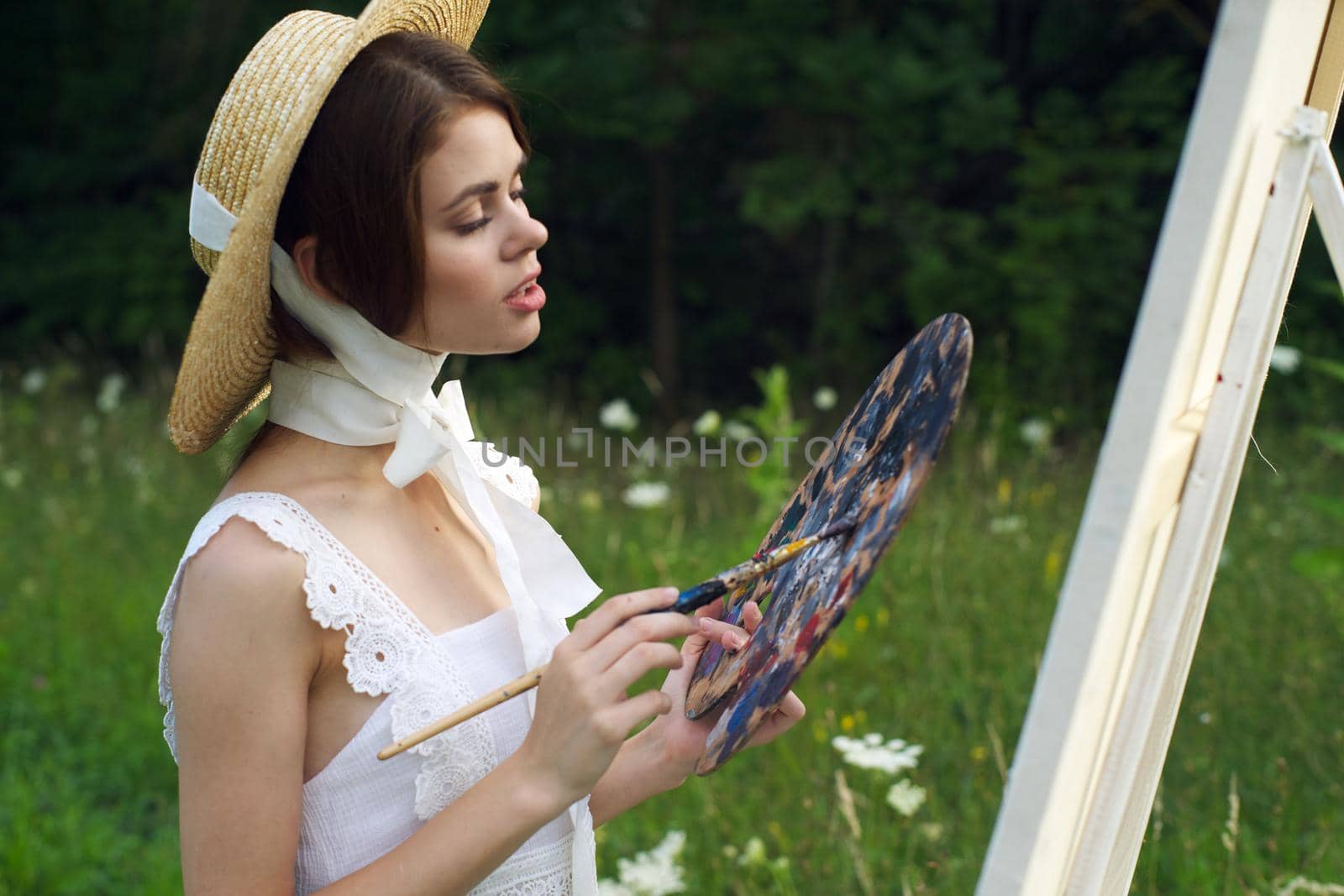 woman with a palette of paints painting a picture outdoors close-up. High quality photo