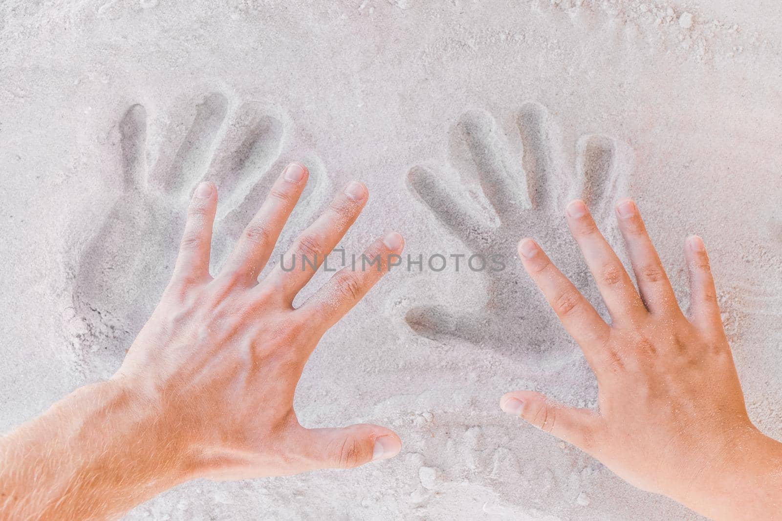 Trail from young male and female hands on white beach sand close-up.