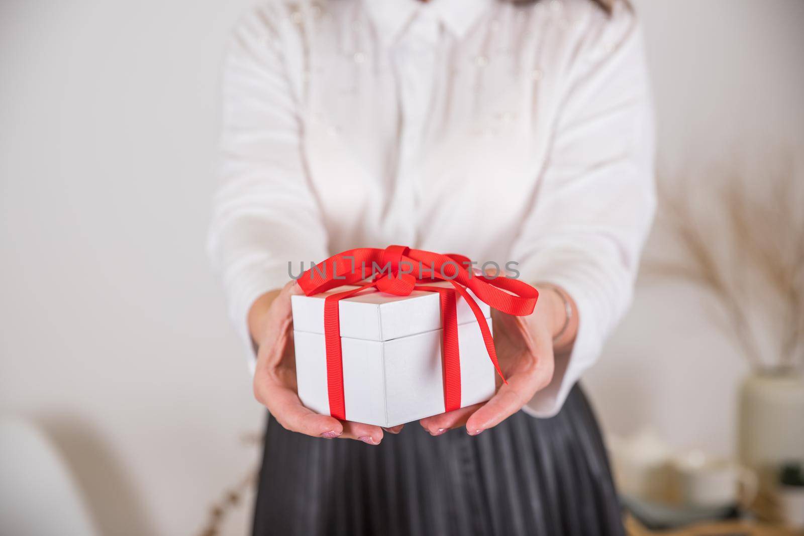 Female hands holding small gift with ribbon.