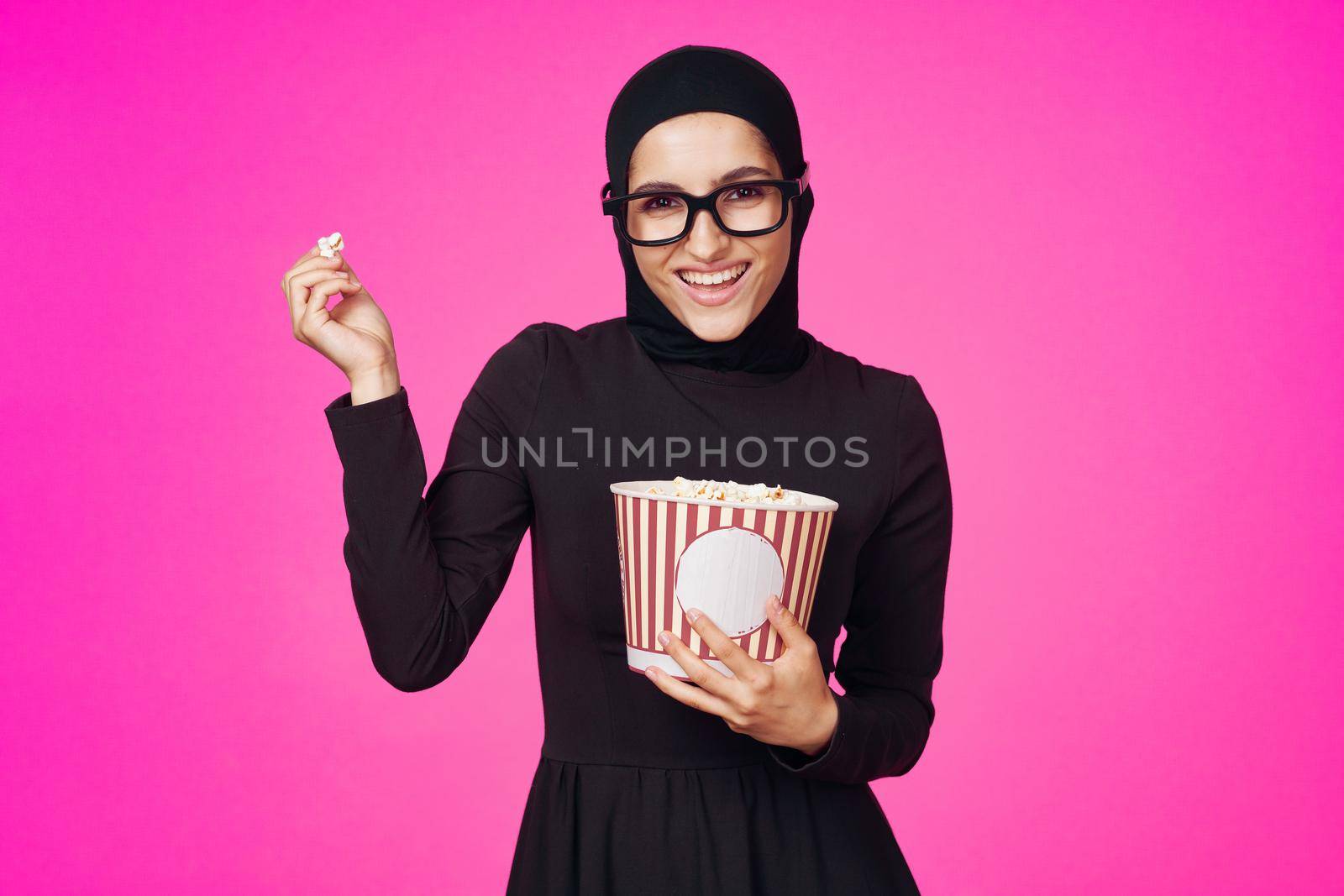 Muslim woman in 3D glasses popcorn entertainment movies isolated background. High quality photo