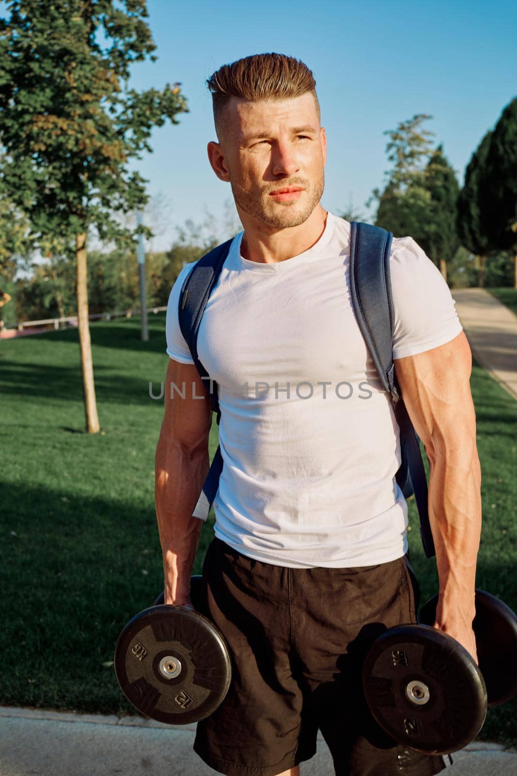 athletic man with dumbbells outdoors at CrossFit park by Vichizh