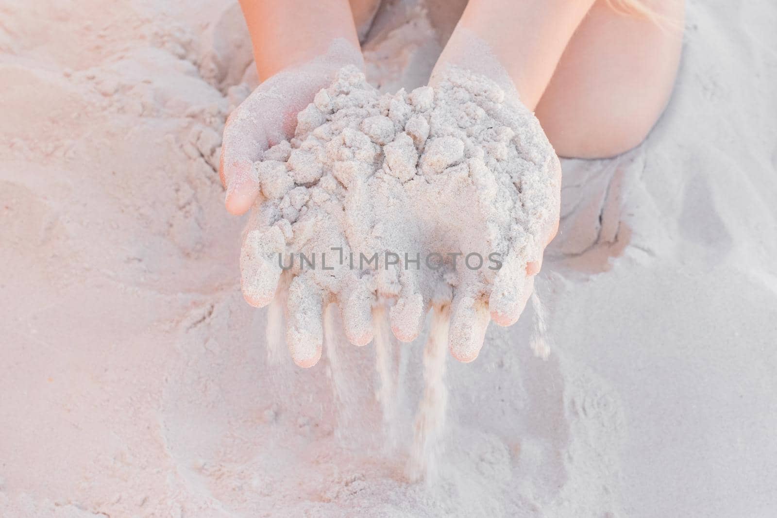 The hands of a young girl hold a pile of white sand close-up by AYDO8