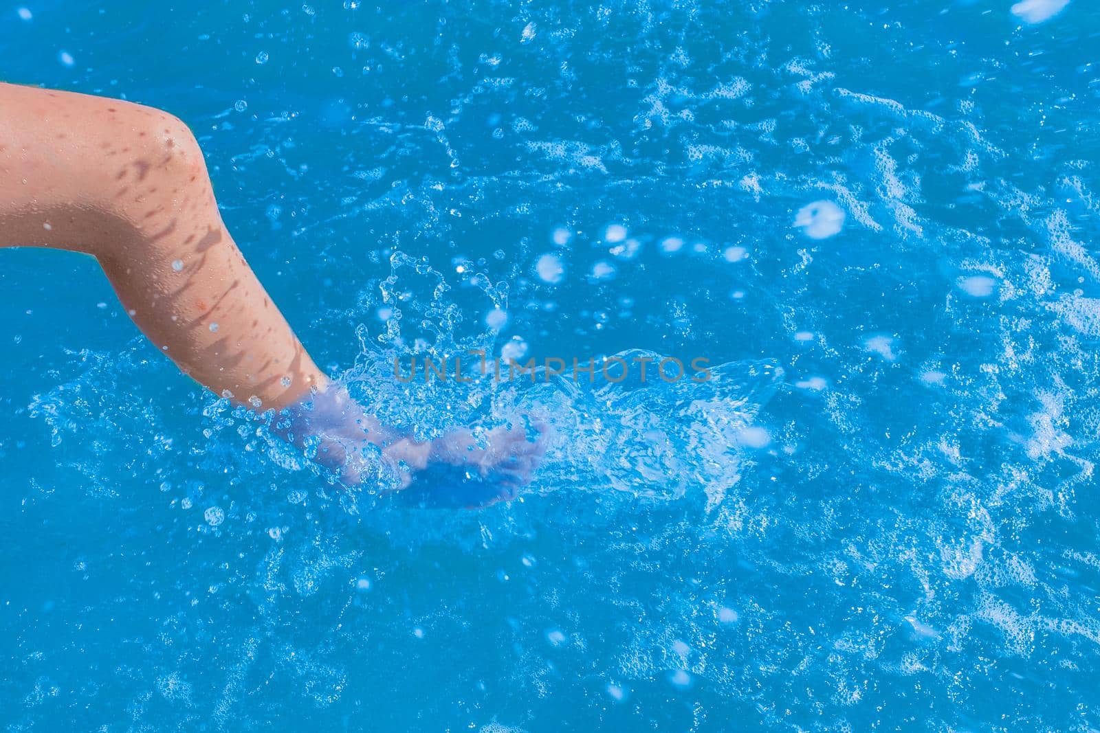 A young girl's leg sprays blue light sea water close-up.