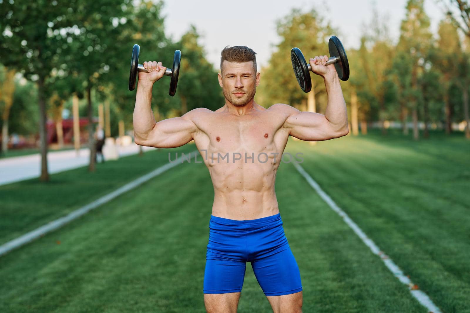 sporty man with pumped up body in park workout exercise by Vichizh