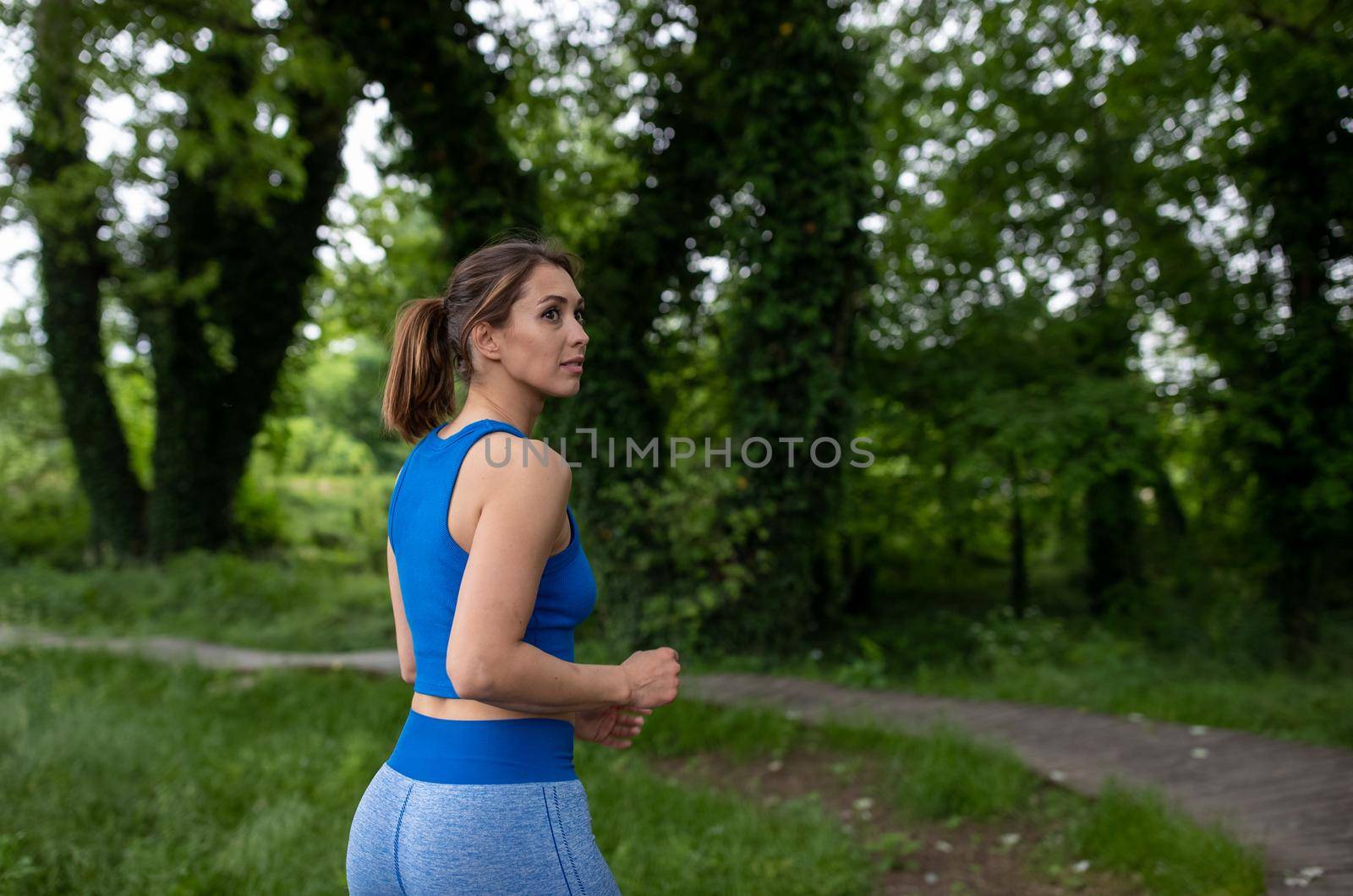 Young female jogger exercising outdoors in nature on dirt path. by budabar