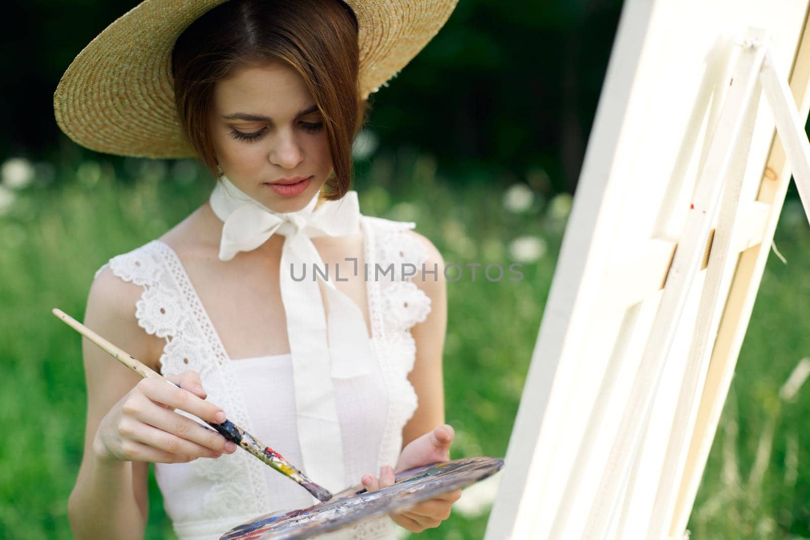 woman artist draws a picture on an easel outdoors by Vichizh