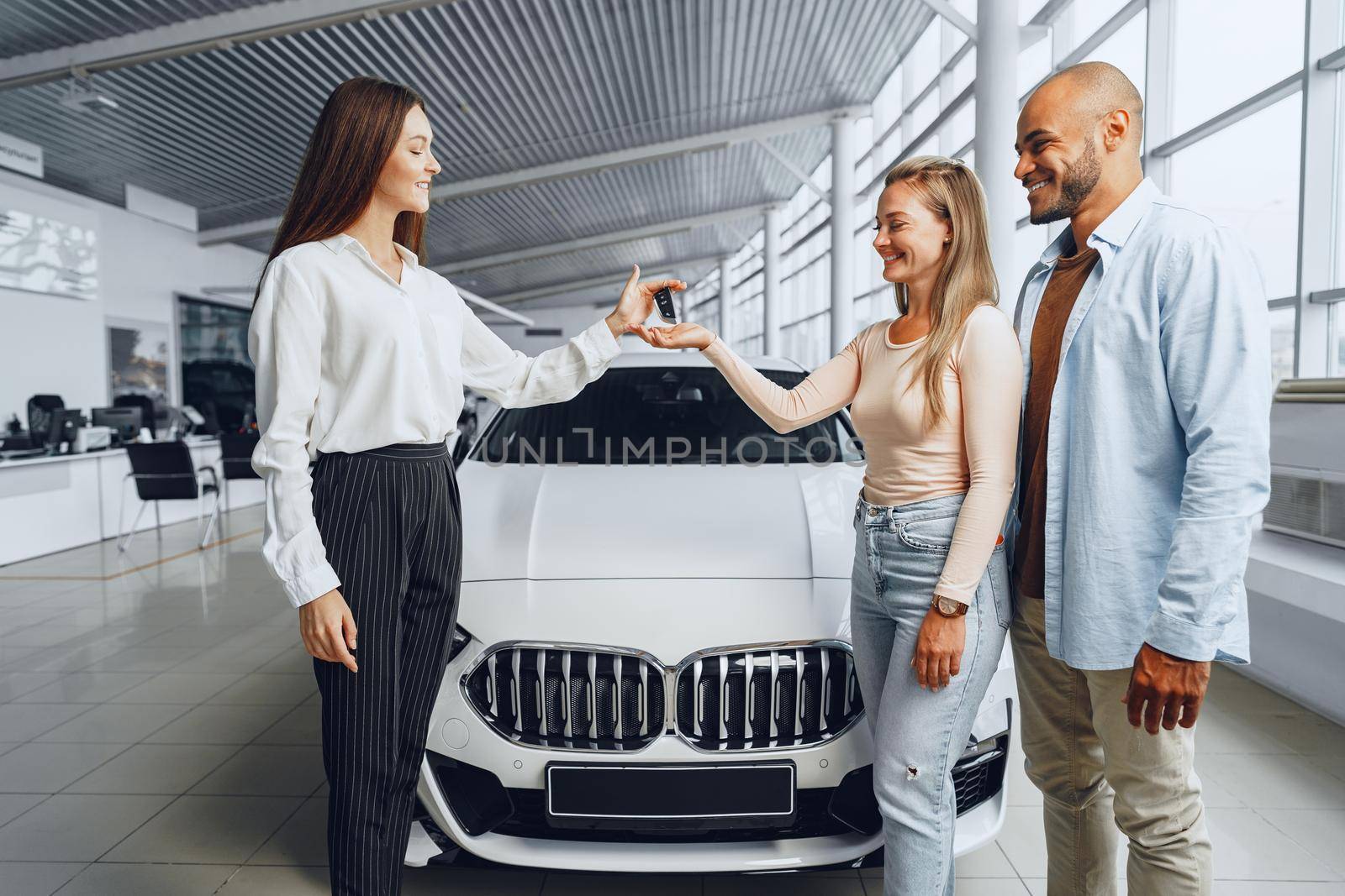 Car saleswoman in a car dealership having a talk with clients buyers