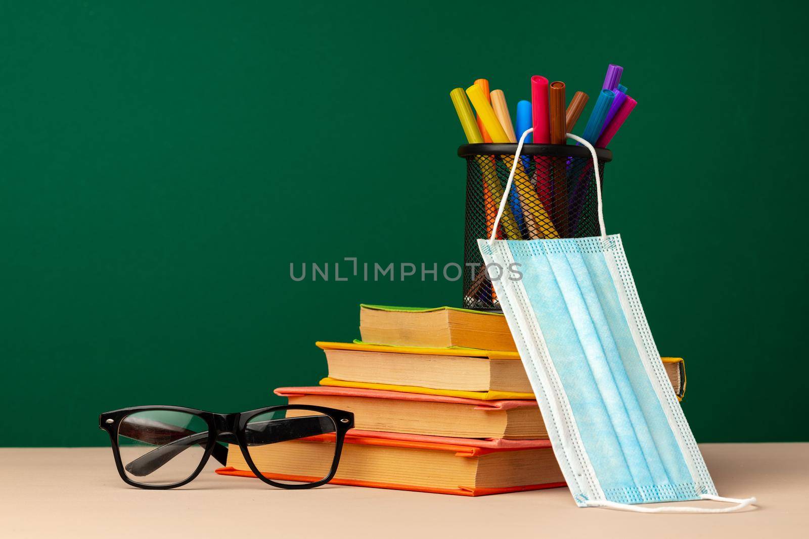 School supplies and medical face mask on desk, copy space
