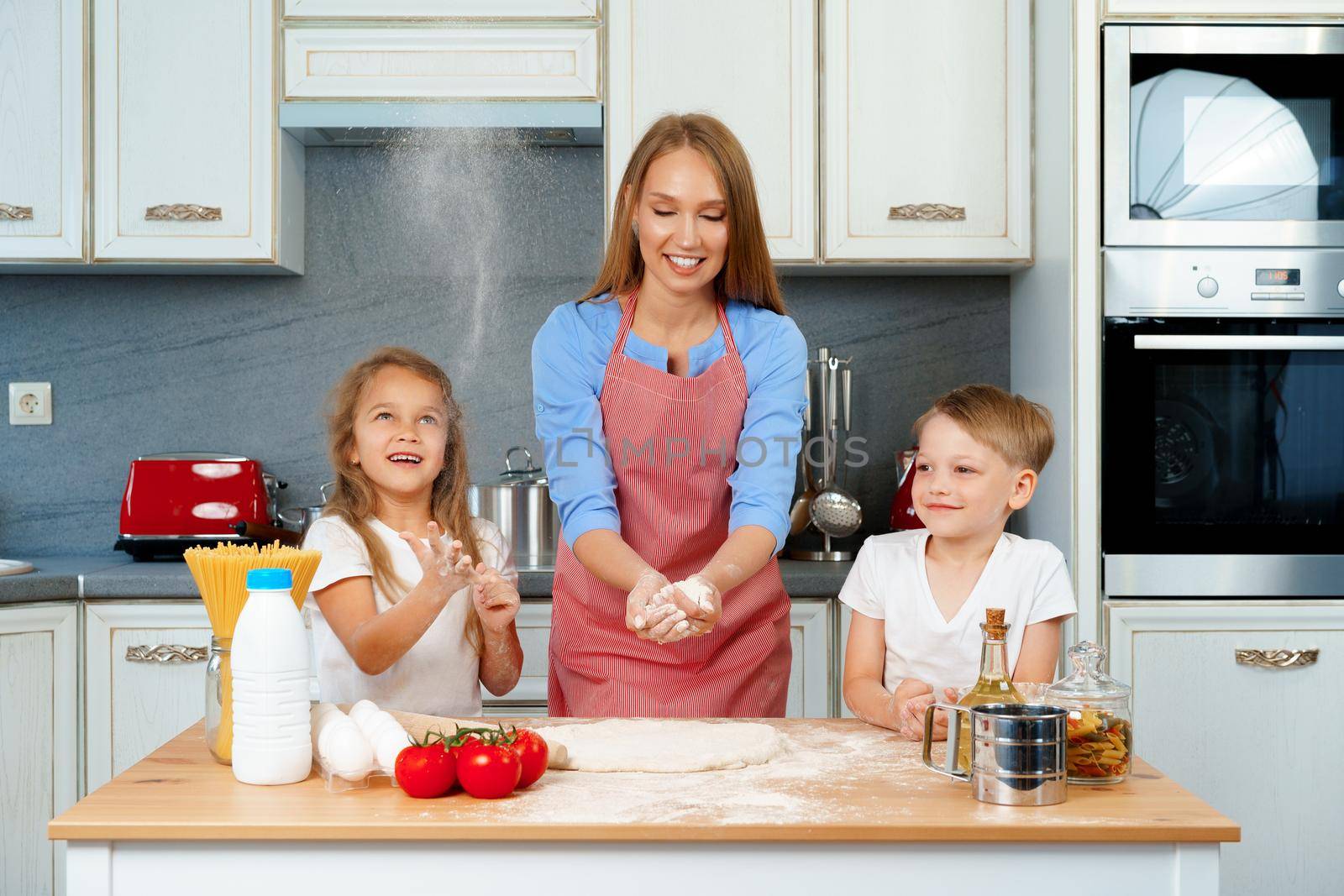 Young blonde woman, mother and her kids having fun while cooking dough close up