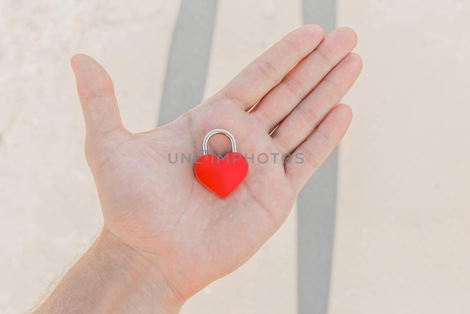 In the man's hand lies a small red heart in the form of a castle, a sign or symbol of love and romantic relationships.