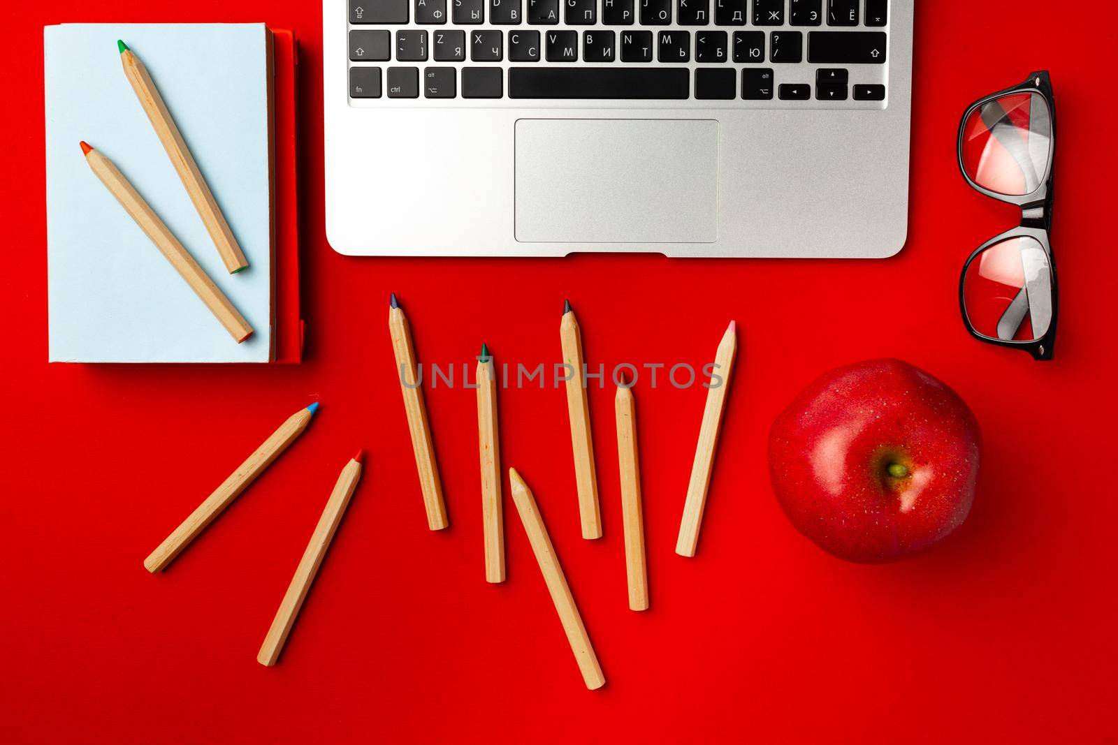 Top view of student working space with open laptop and red apple, other supplies