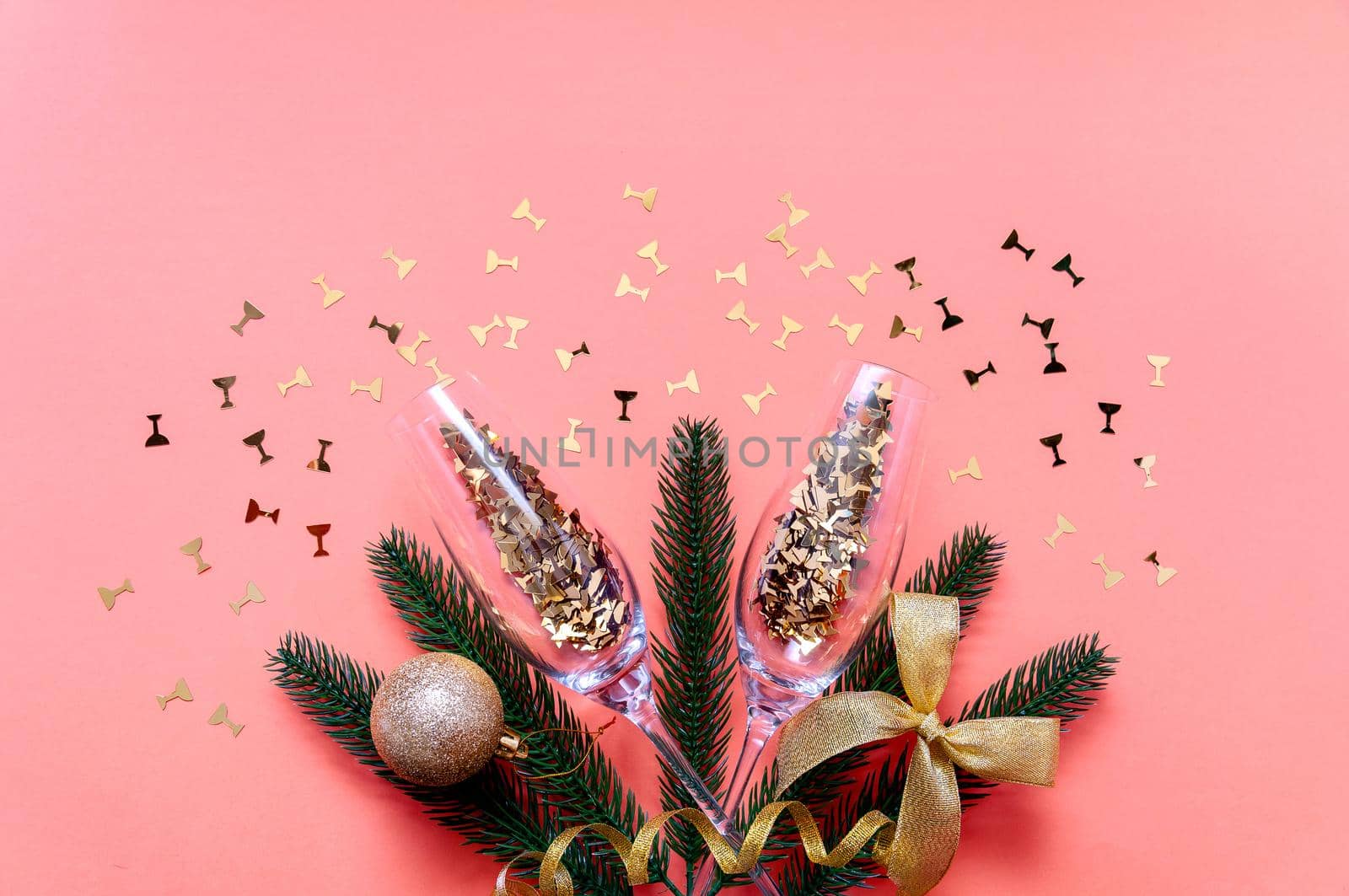 Champagne Glasses with Golden Confetti and Branches Fir Tree on Pink Background. Creative Christmas Concept.