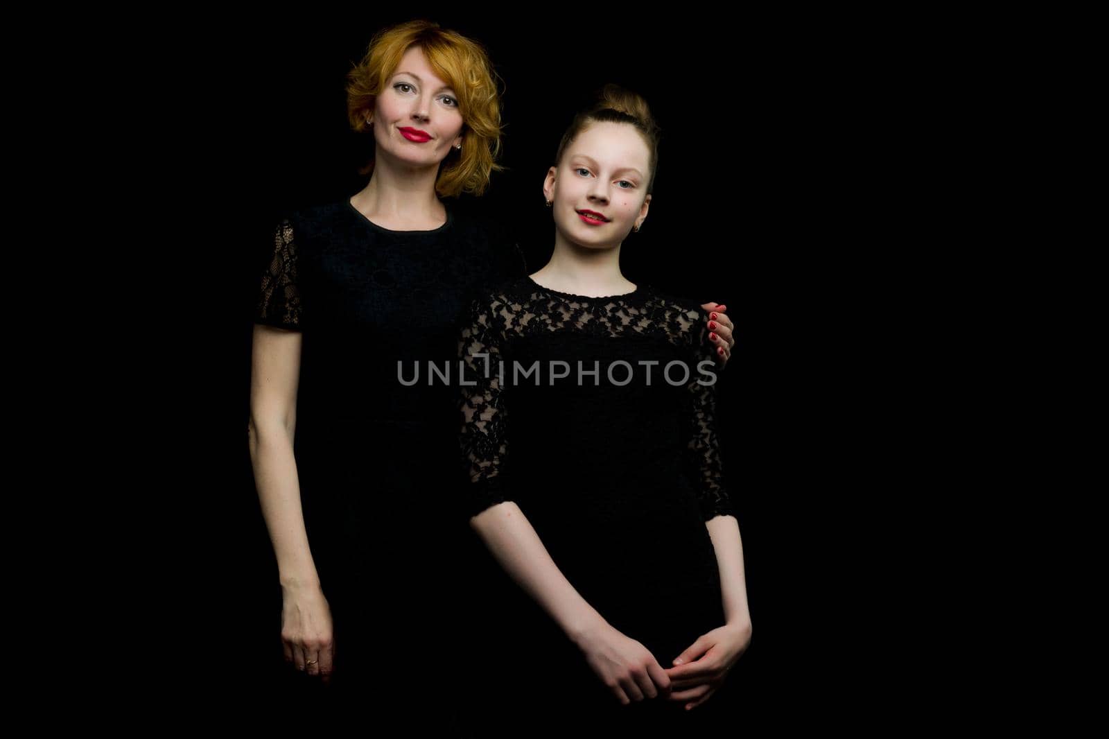 Happy family mom and little daughter, studio portrait.On black background