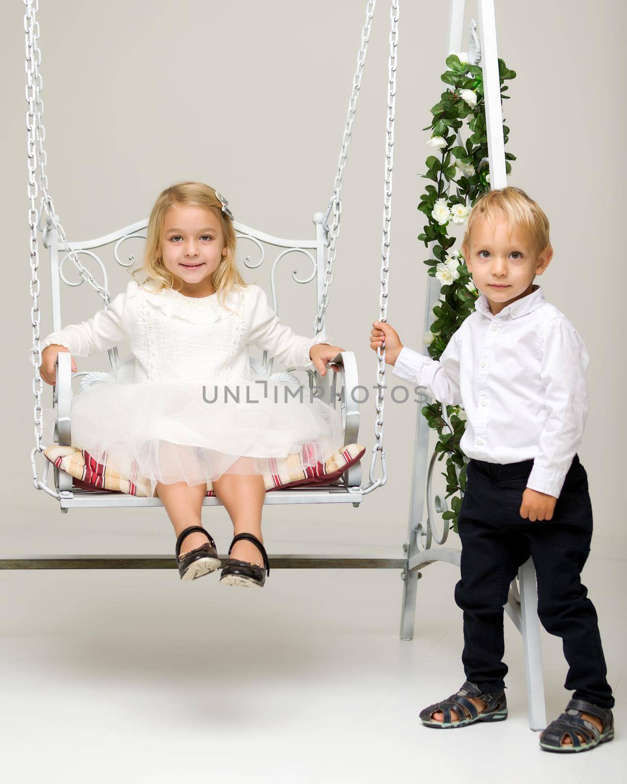 Little boy and girl swinging on a swing. by kolesnikov_studio