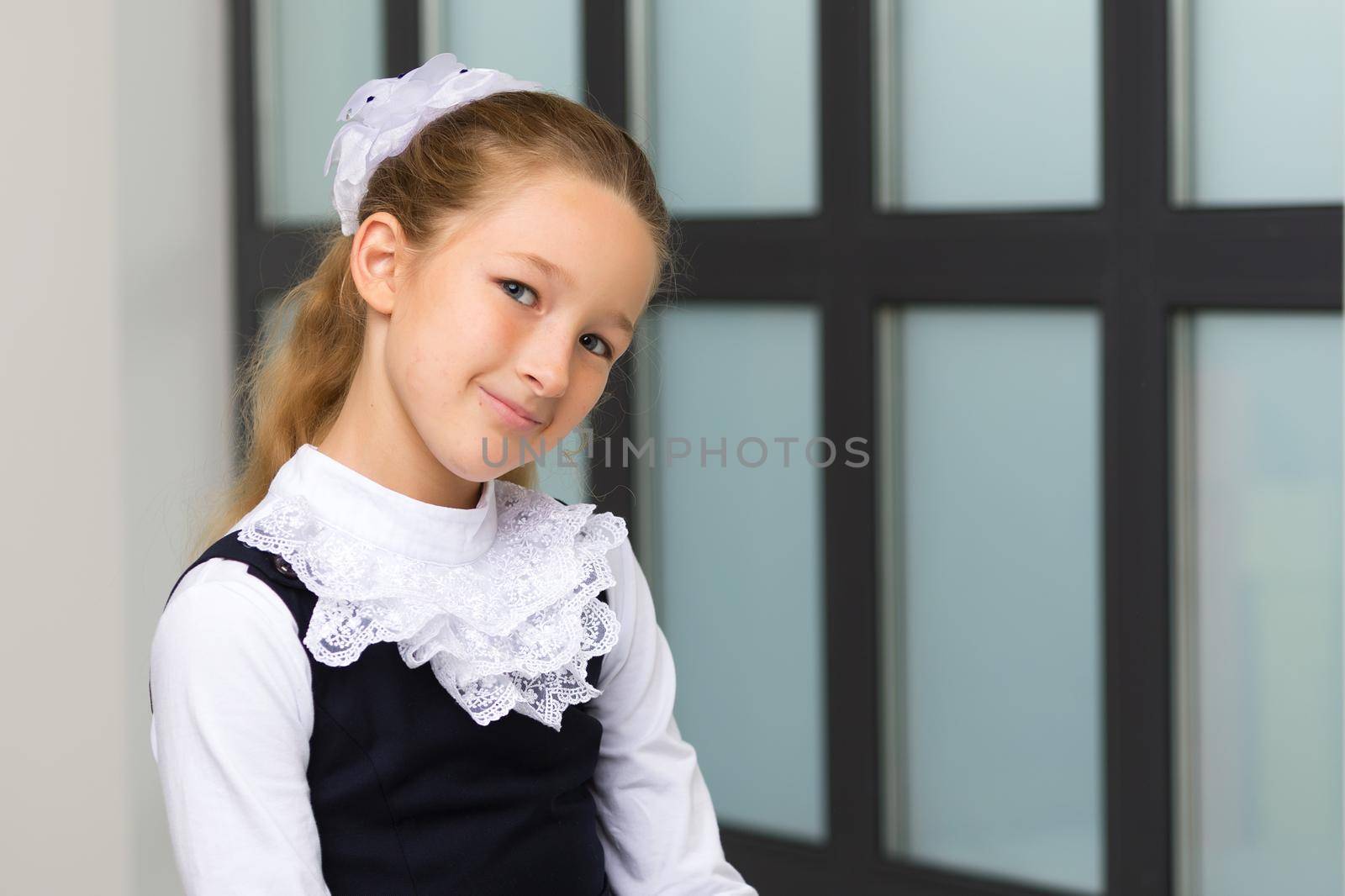 Cute little girl in school uniform near a large panoramic window.