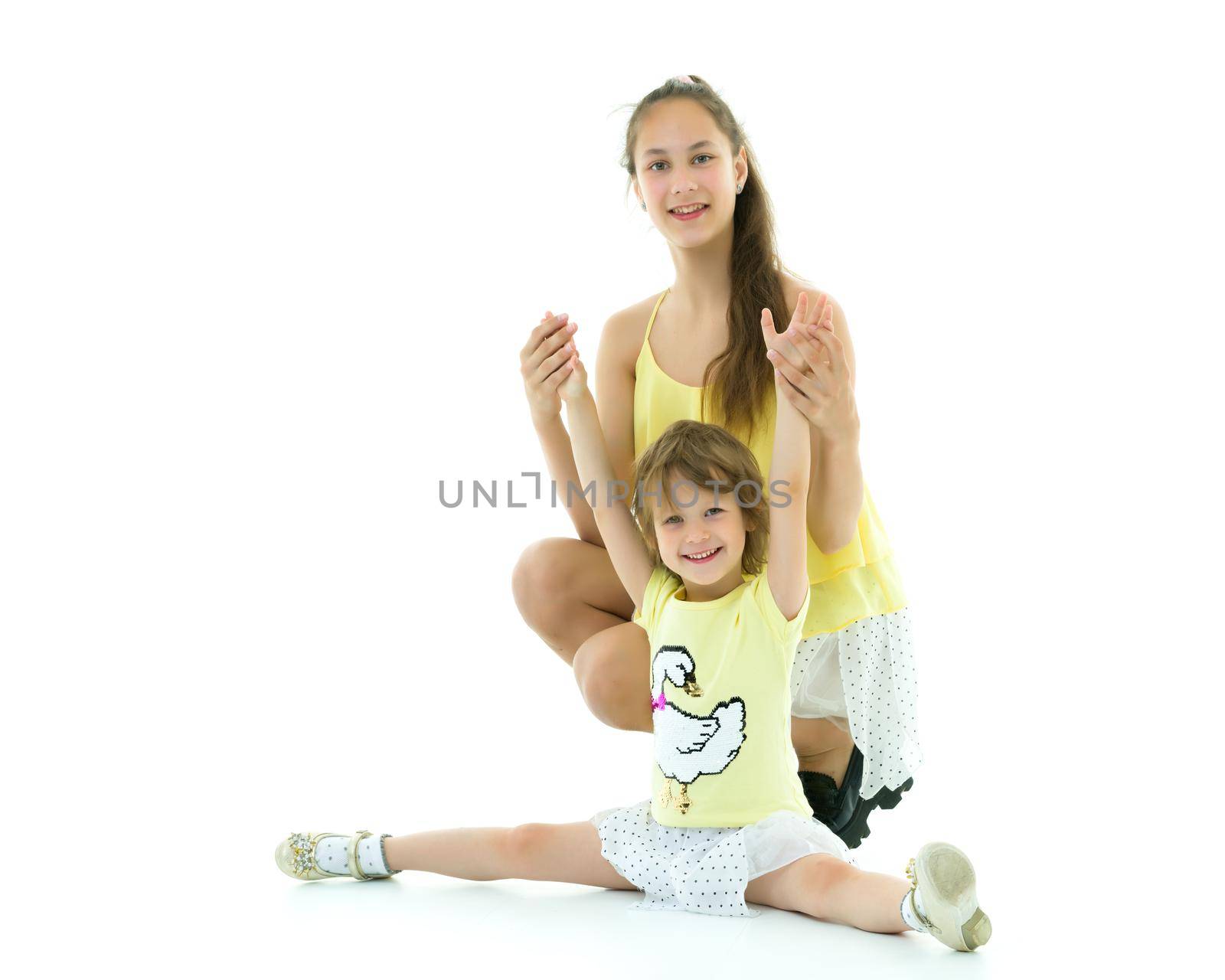 Two older and younger girls, two sisters fun posing in the studio. The concept of family, friendship. Isolated on white background.