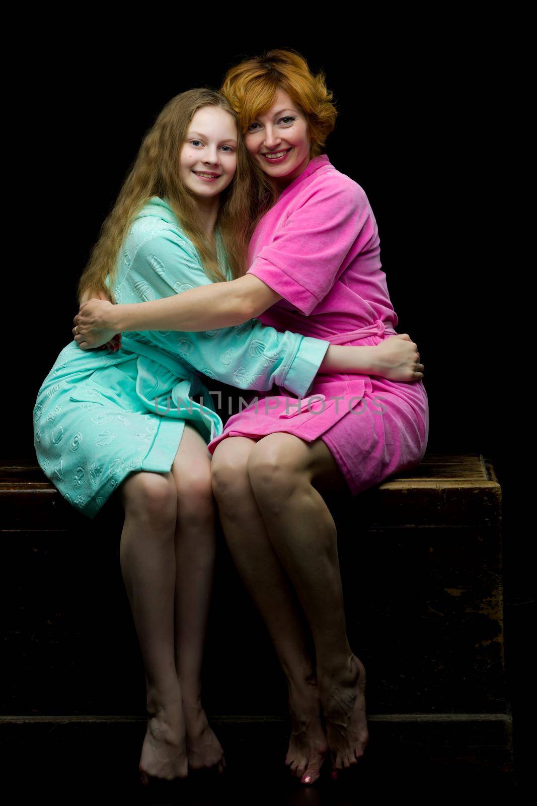 Daughter and mother in bath robes in a photo studio. The concept of relaxation, cosmetics. Isolated