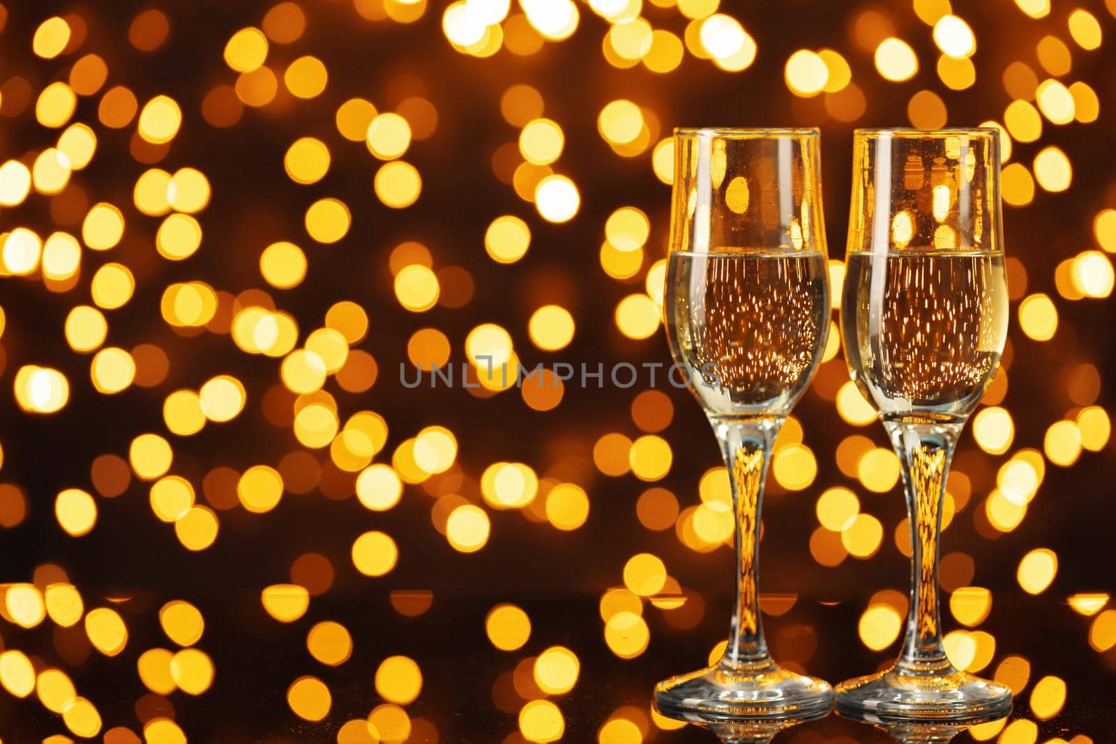 Two glasses of Champagne against shiny bokeh lights background