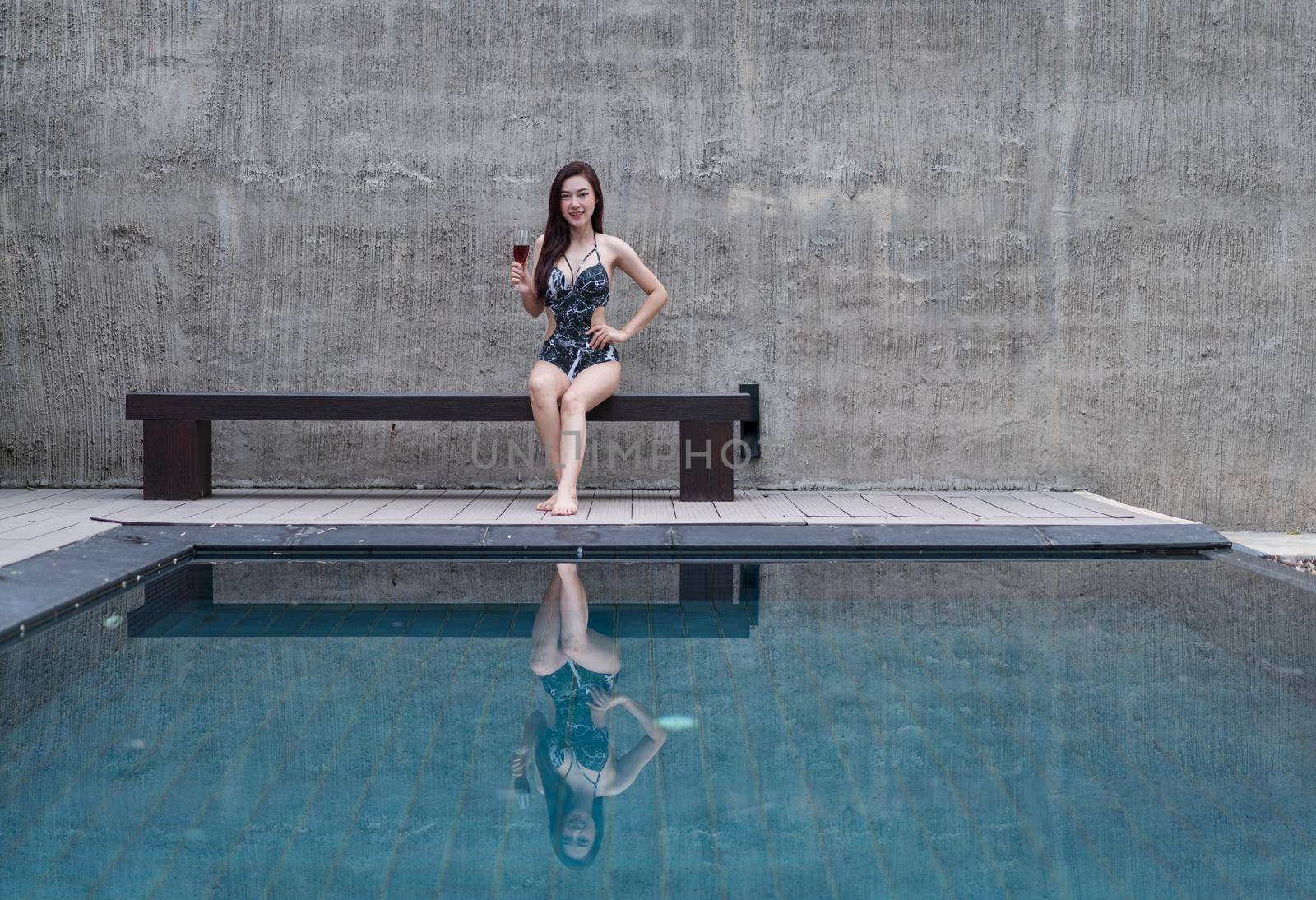 woman resting on chair and holding a glass in swimming pool