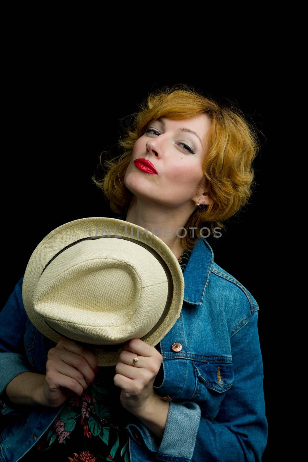 Beautiful young woman with a hat. Studio photo on black background.