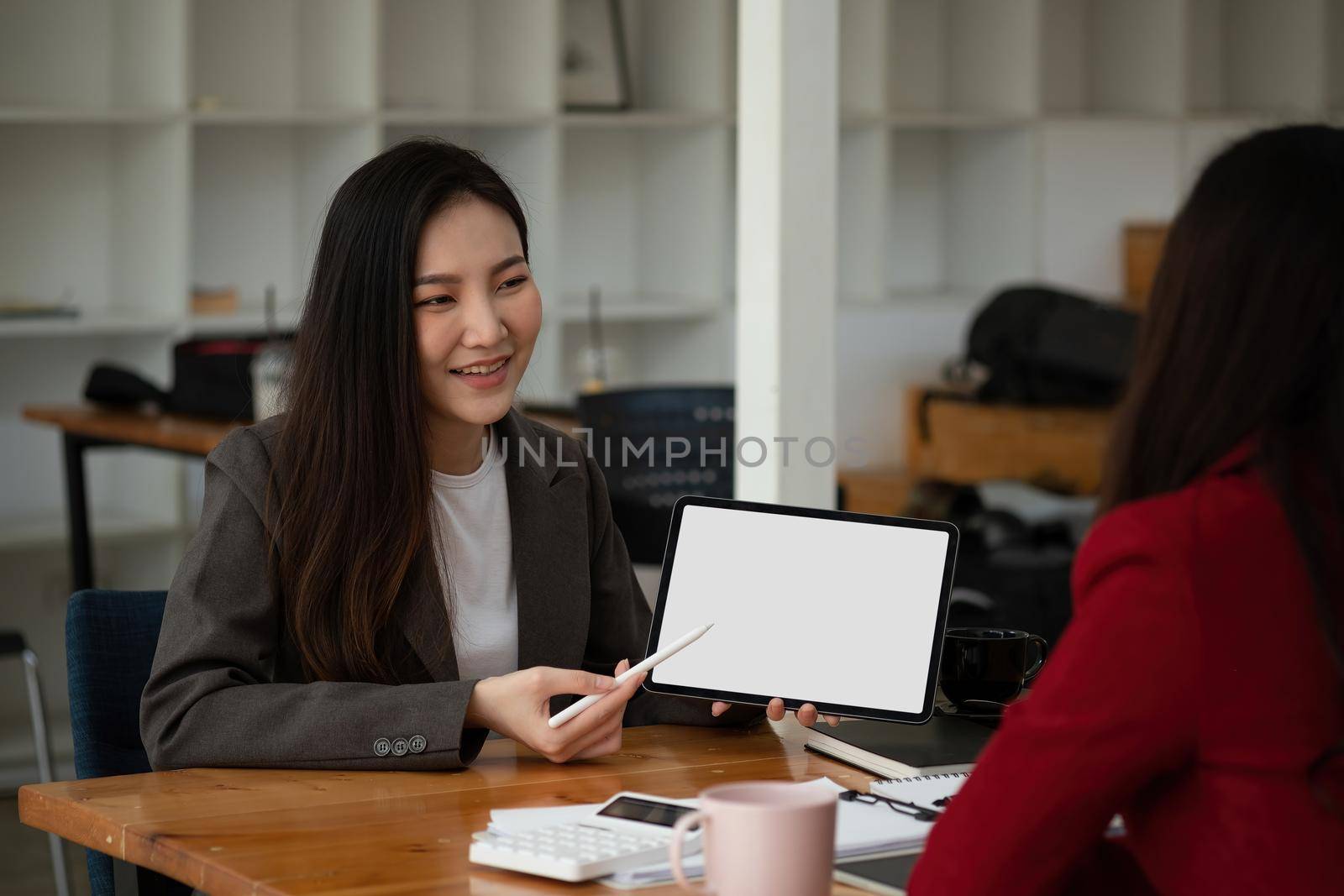 Group of young business people brainstorming at a meeting starting a new business with blank white screen tablet