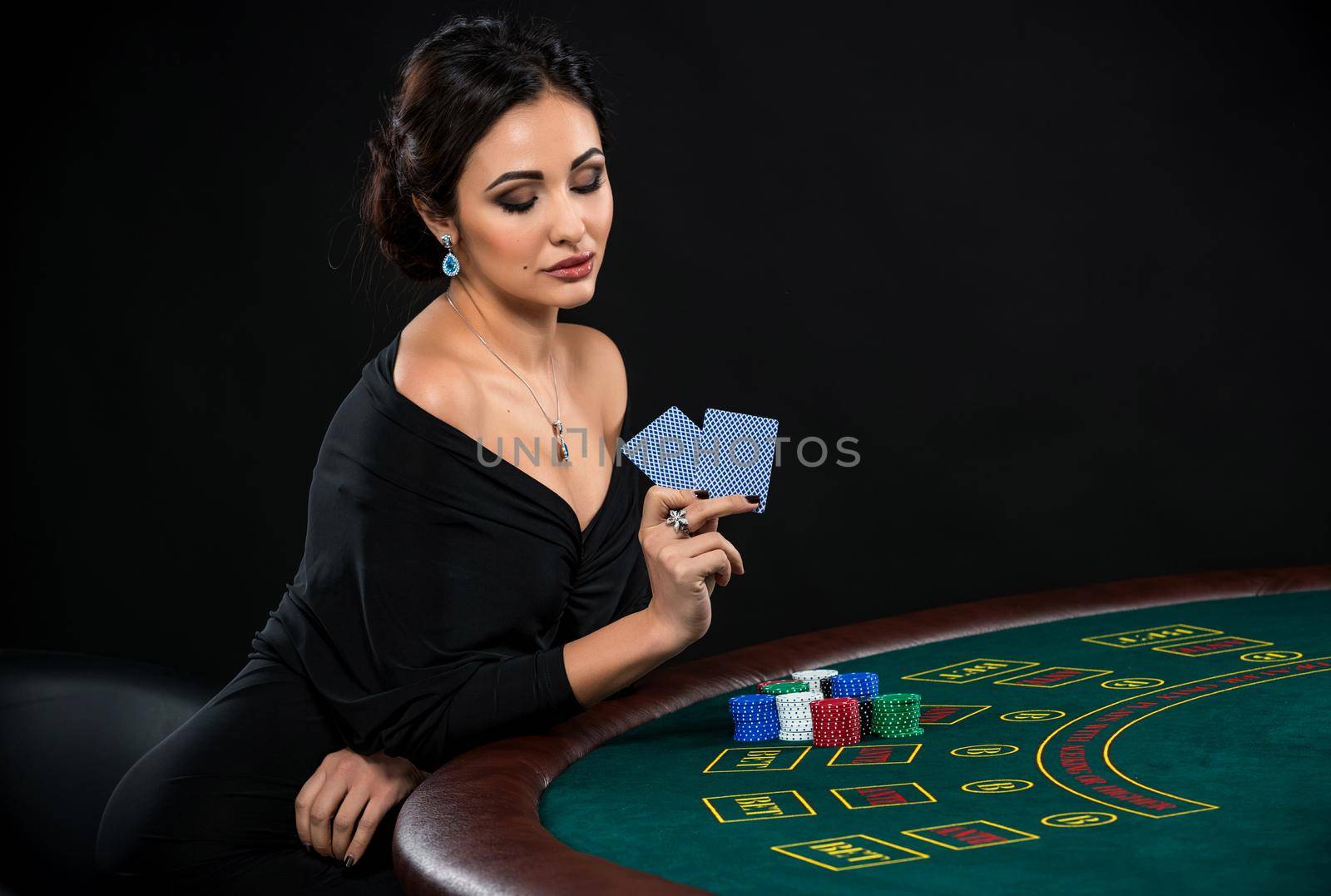 sexy woman with poker cards and chips. Female player in a beautiful black dress