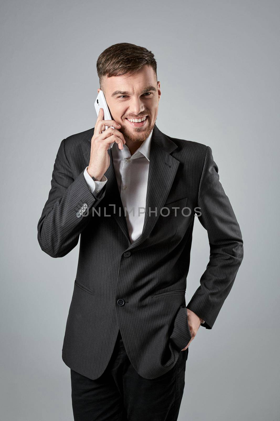 Portrait of a handsome businessman making a phone call against a grey background. Emotions