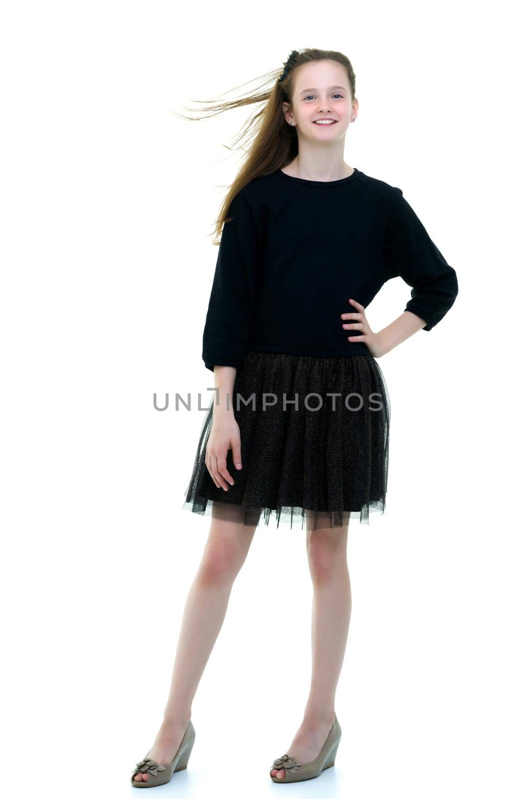 Beautiful little school girl with long silky hair. Studio portrait in full growth. Concept of style and fashion, happy people. Isolated on white background.