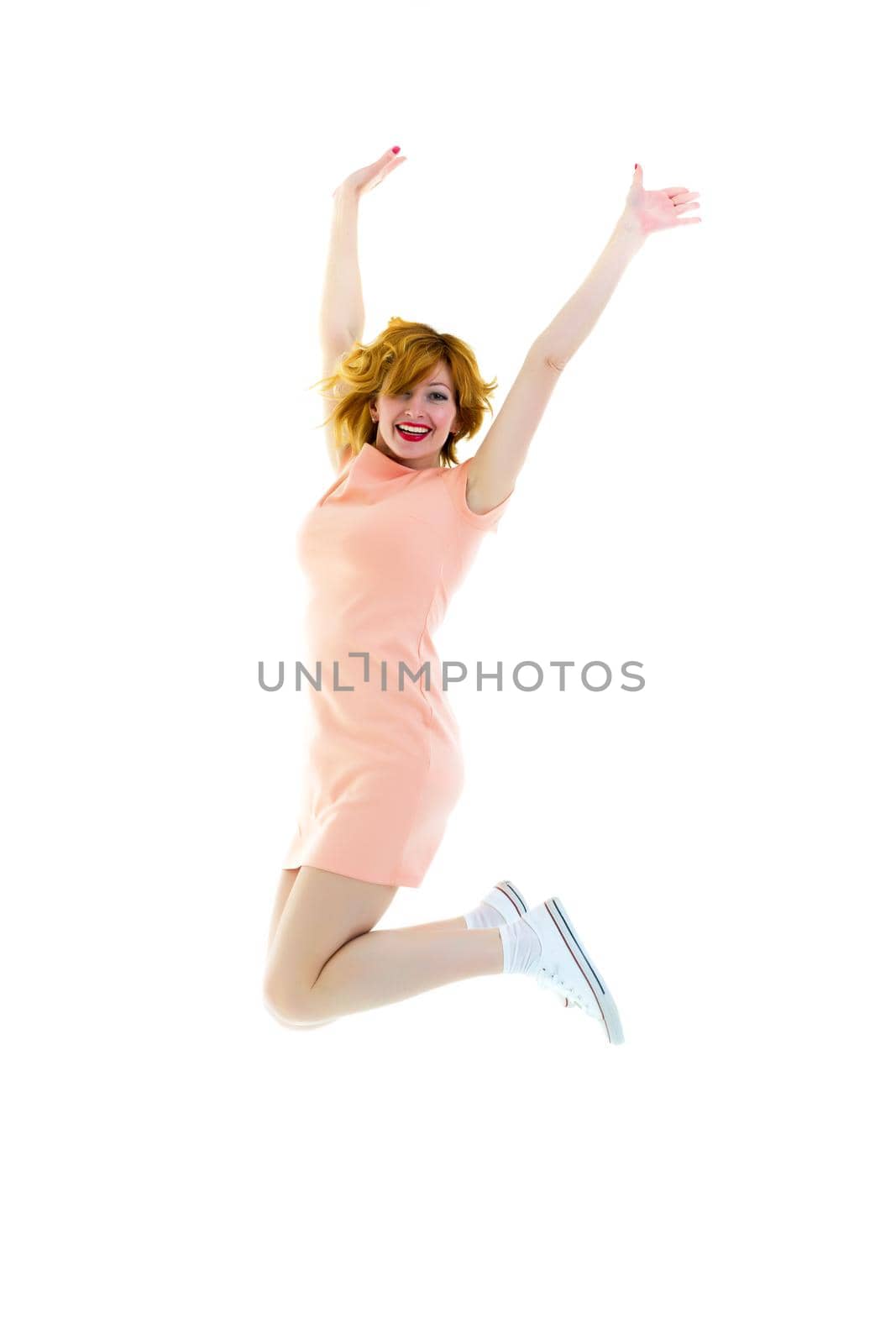 Cheerful young woman is jumping in a photo studio. Isolated on white background