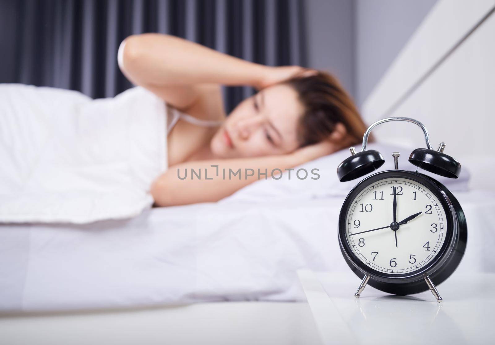 clock with woman sleepless on the bed 