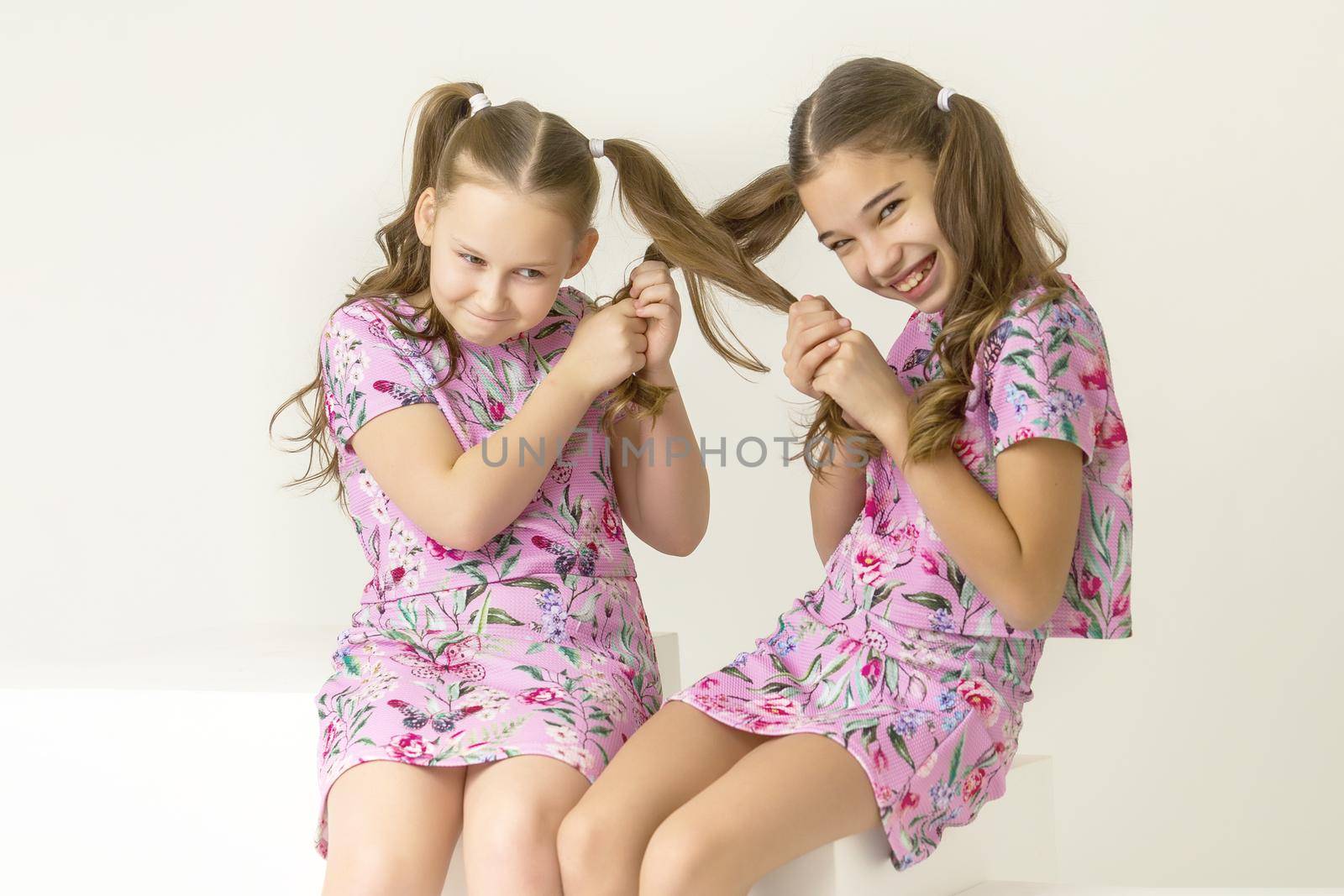 Kind funny girls pull each other for pigtails. The concept of tenderness and beauty.