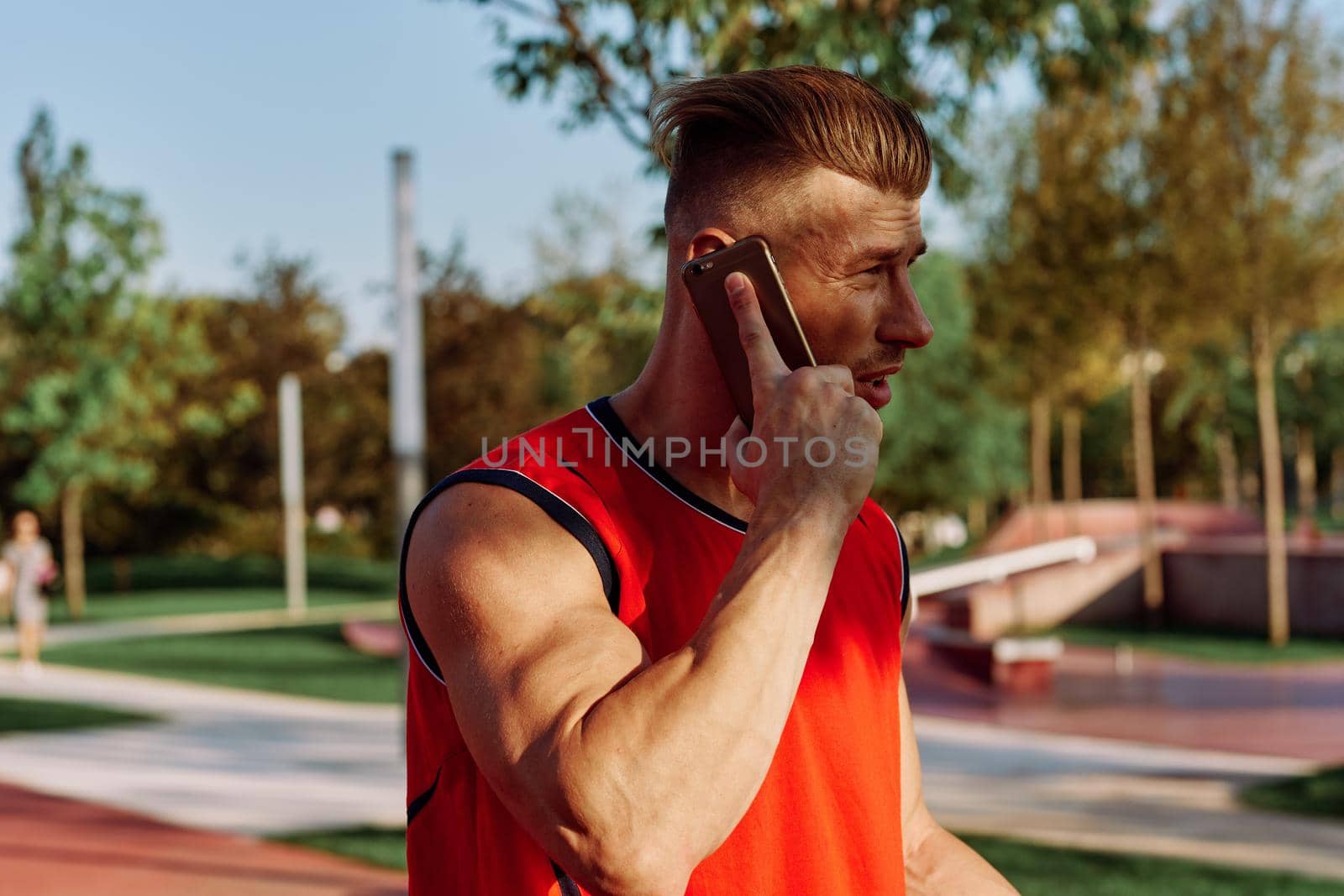 athletic man talking on the phone in the park by Vichizh