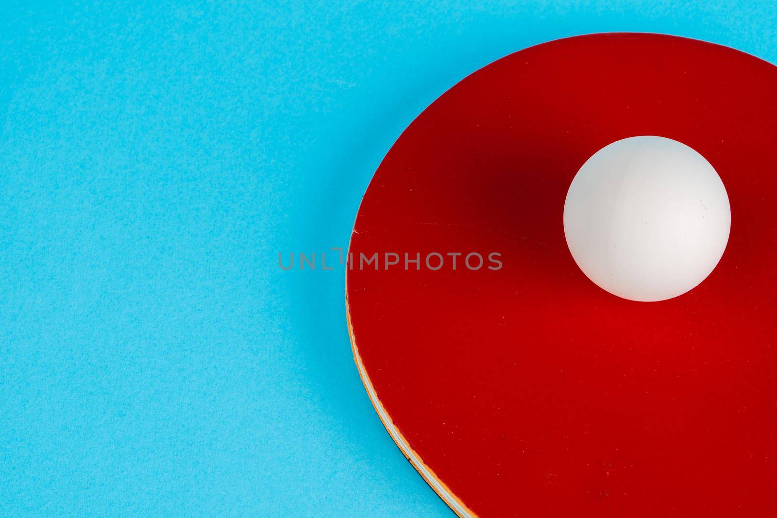 Red ping pong racket on a blue background. Close up.