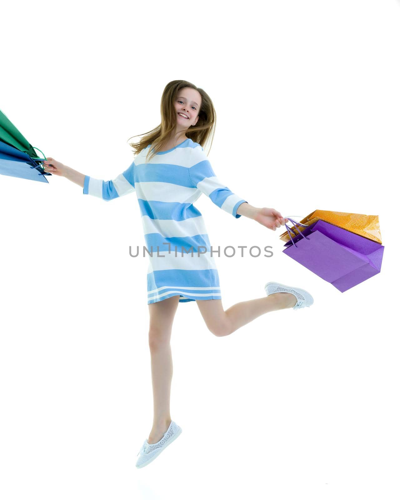 A cheerful little girl is shopping in a store with large, multi-colored paper bags. The concept of holidays, advertising sales. Isolated on white background.