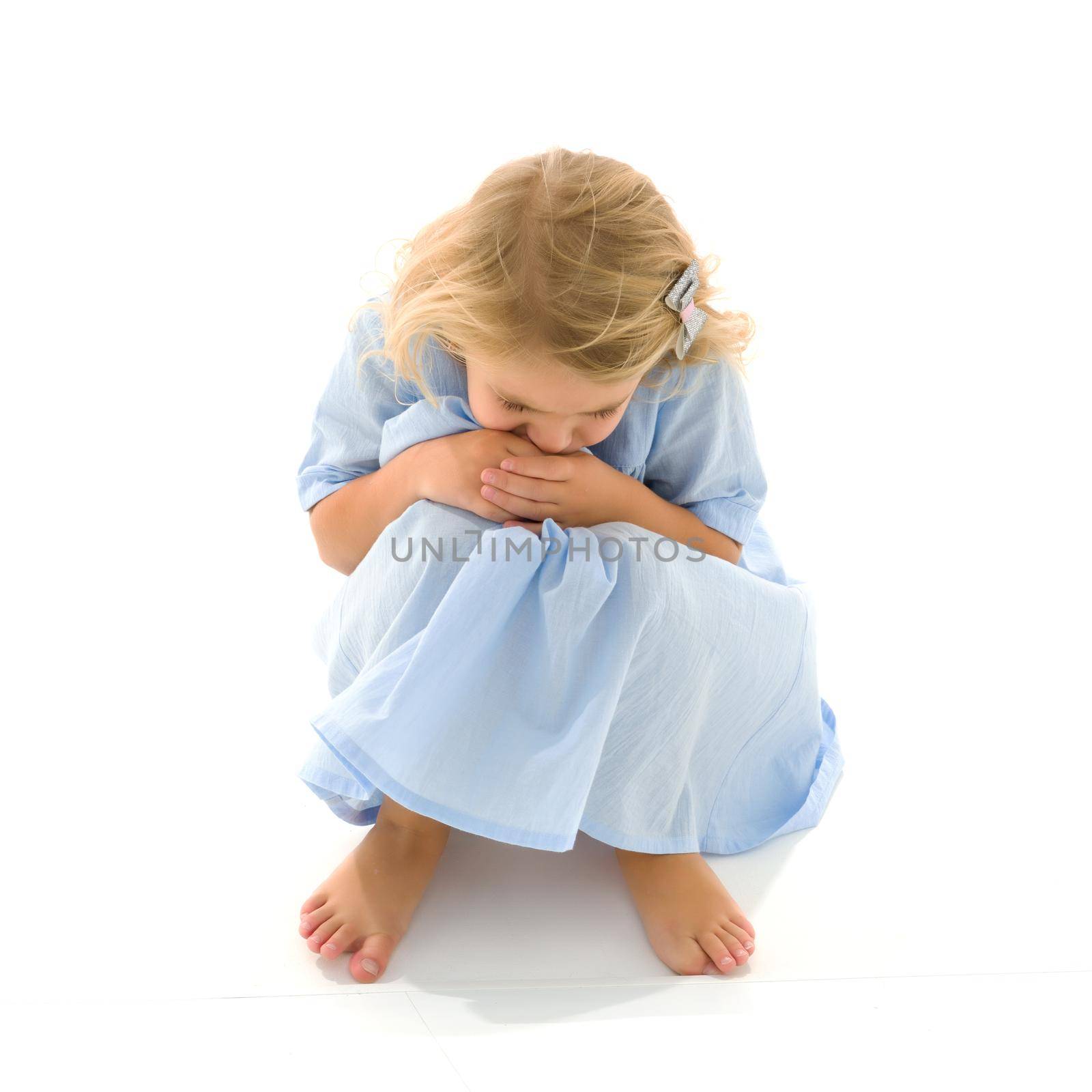 A cute little girl was offended, having turned away from the camera, she covered her head with her palms. Isolated on white background.