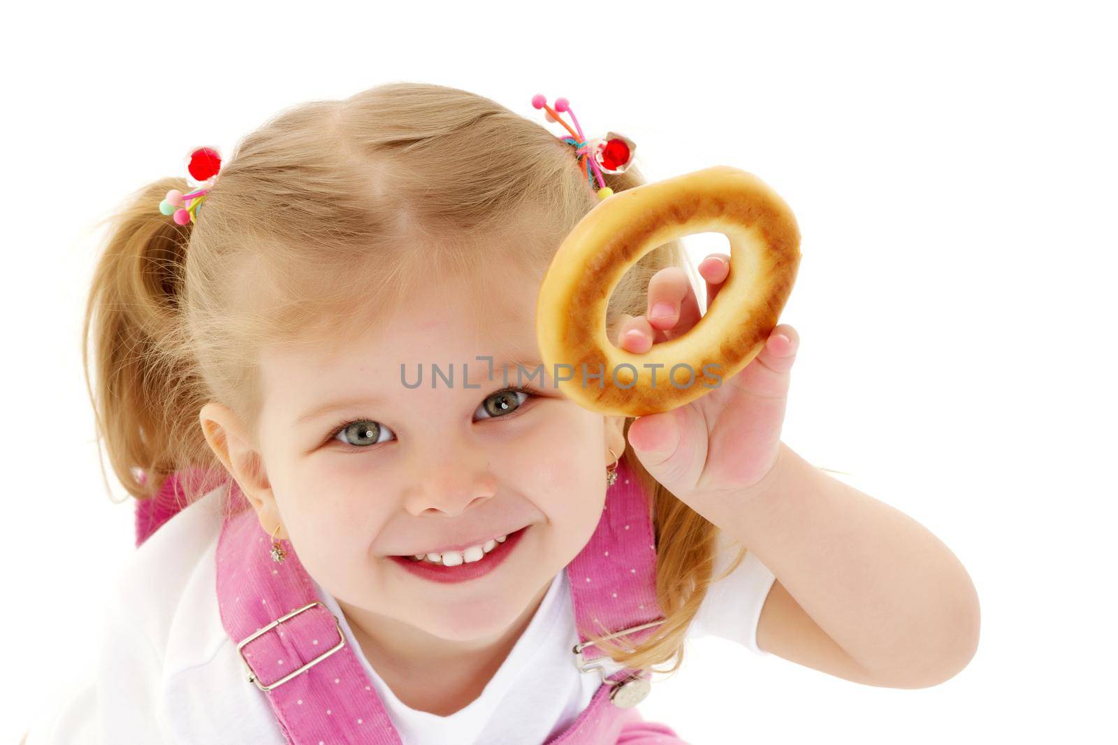 The little girl is eating a bagel. The concept of a healthy baby food. isolated on white background