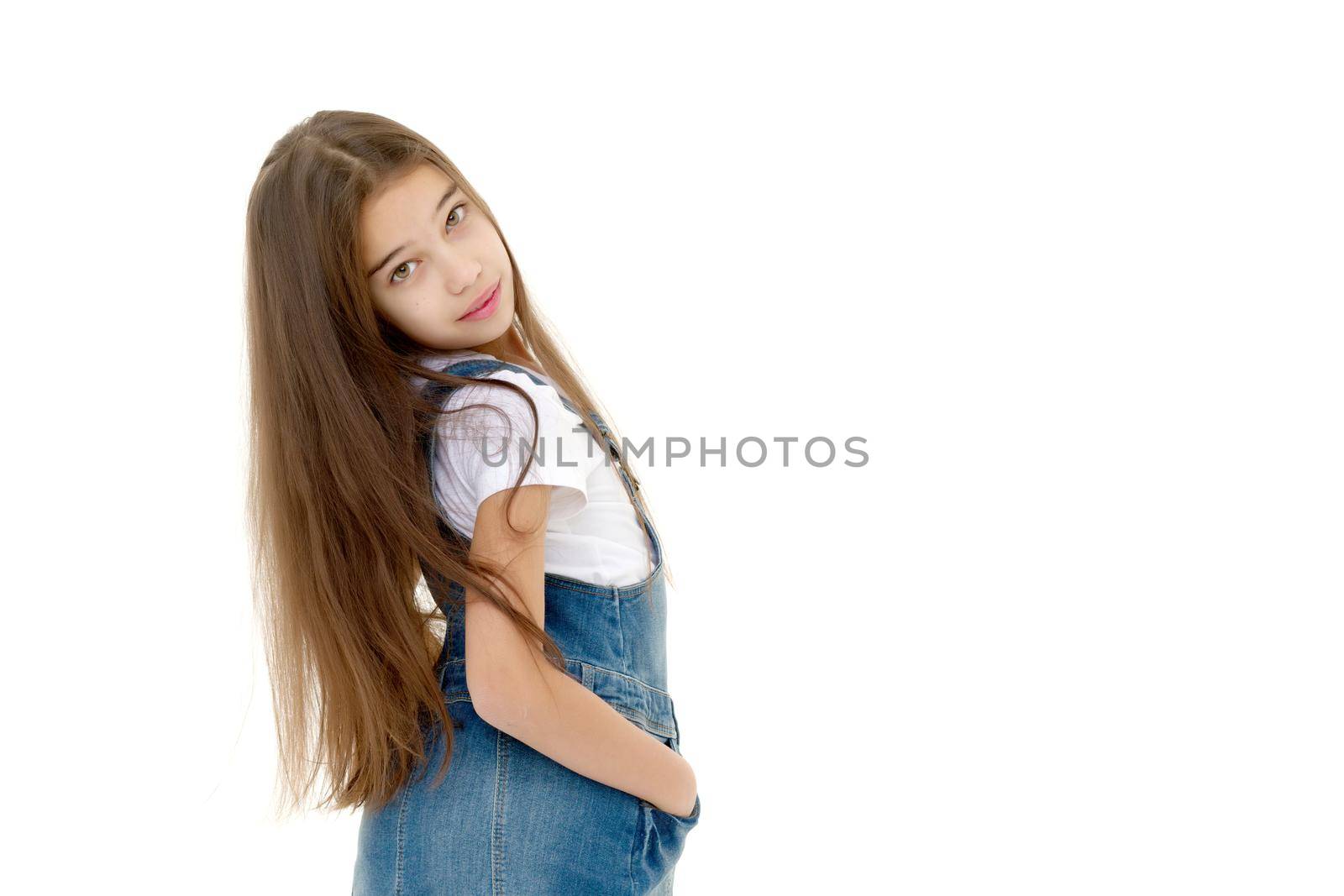 Beautiful little girl in a short denim dress. Concept of beauty and fashion, happy childhood. Isolated on white background.
