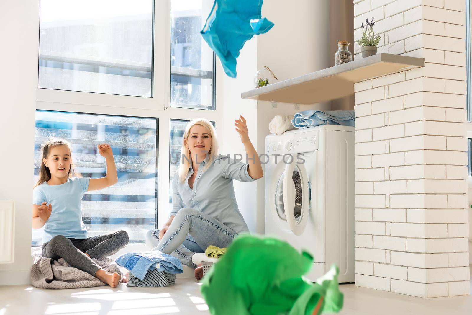 family mother and child girl little helper in laundry room near washing machine and dirty clothes