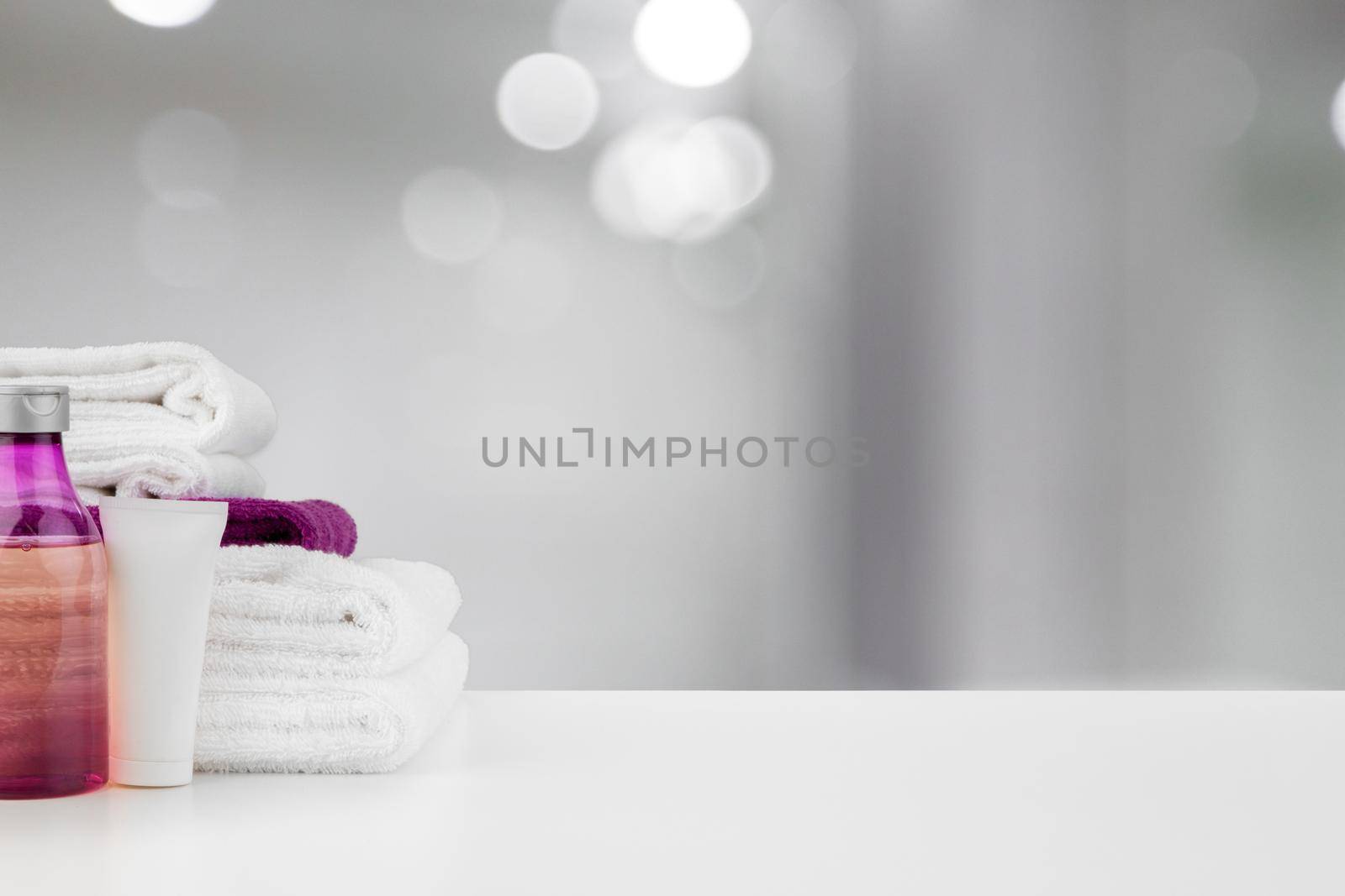 Spa still life with towels and skincare cosmetics against blurred background, close up