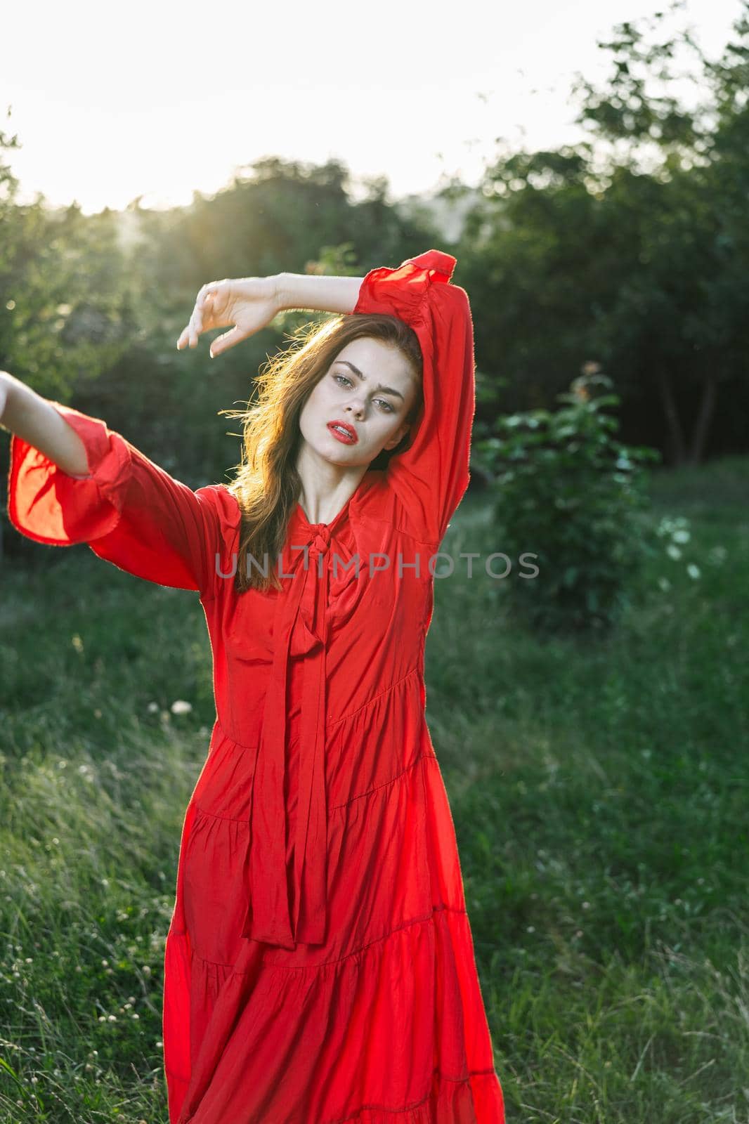 attractive woman in red dress posing in nature green grass. High quality photo