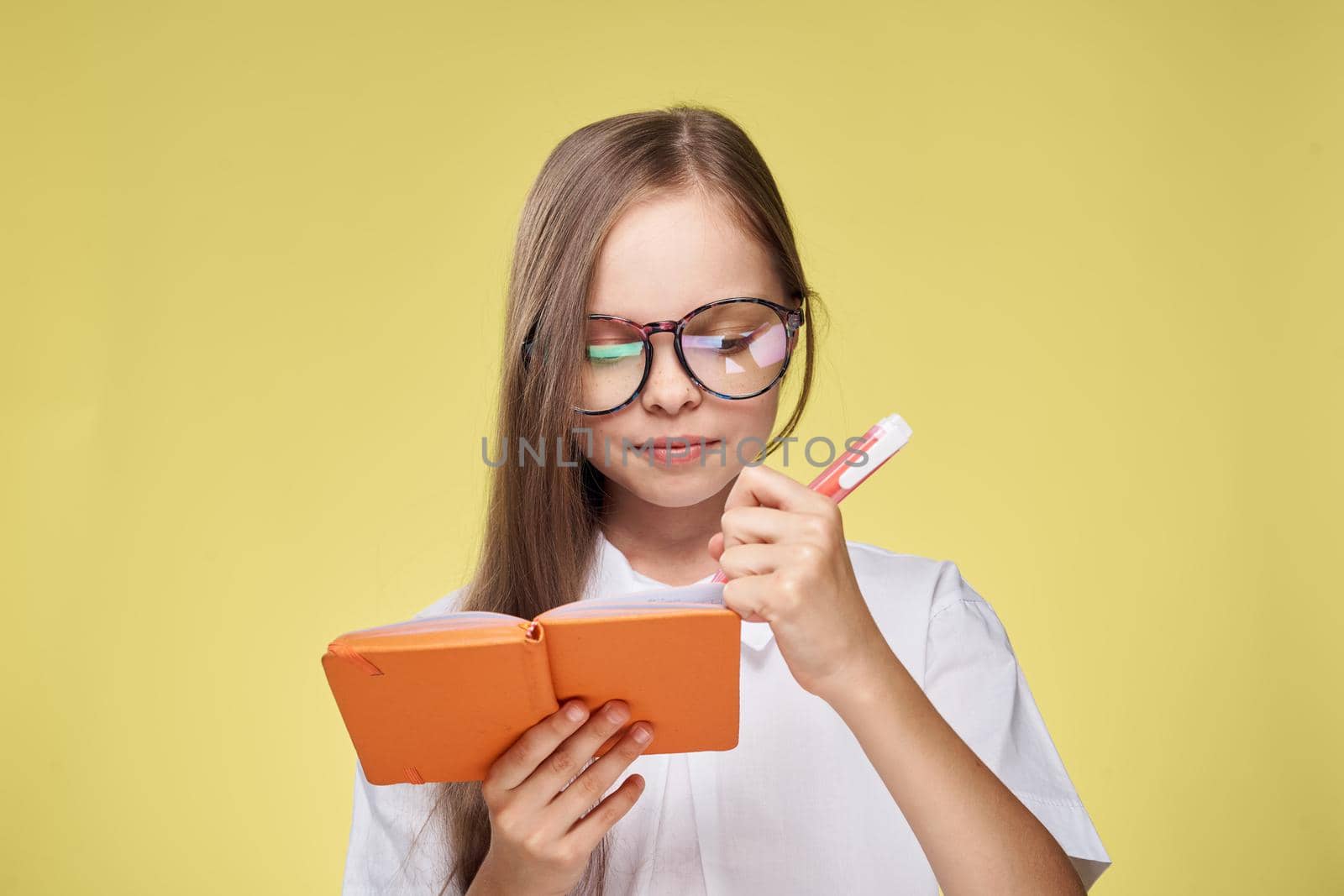 schoolgirl with textbook in hands learning childhood yellow background by Vichizh