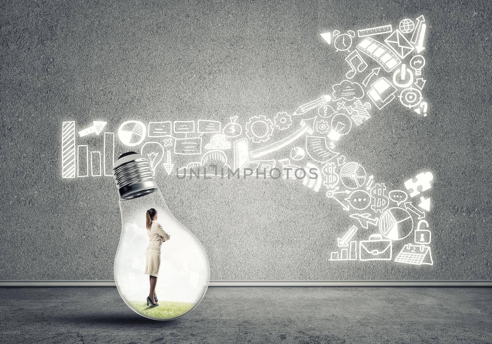 Businesswoman inside of light bulb in empty concrete room