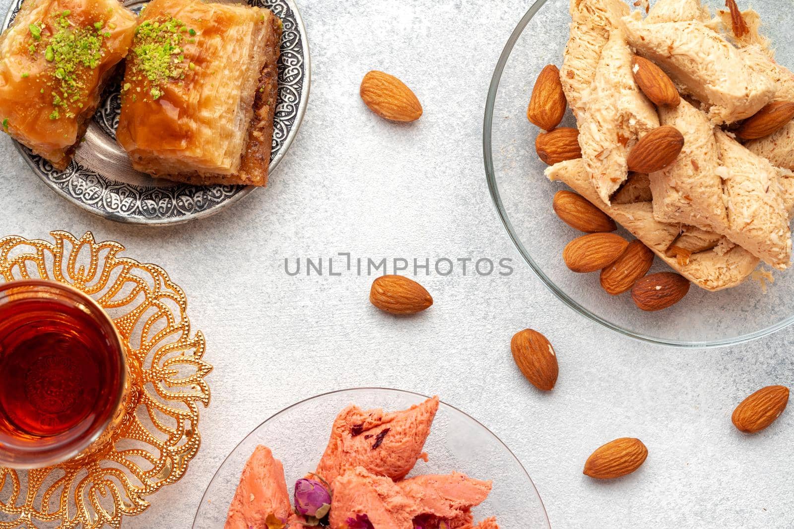 Assortment of Turkish delights with glass of tea on gray background, close up