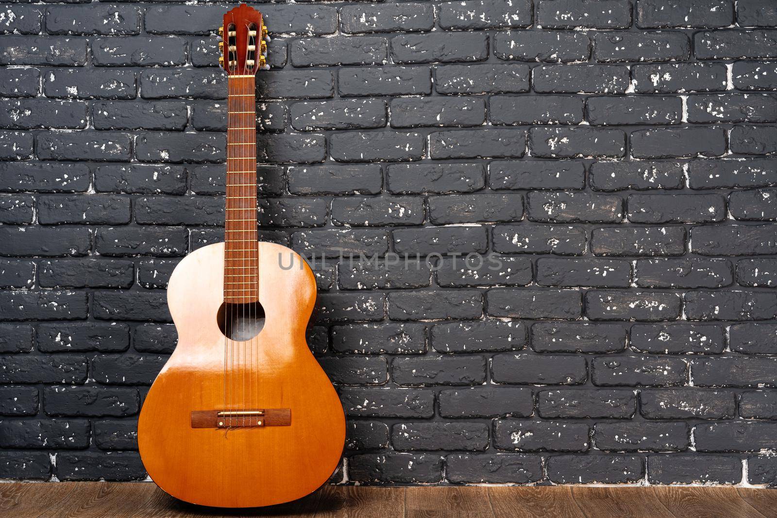 One guitar on the floor against white brick wall, copy space